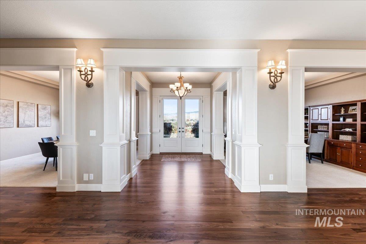 Entryway with decorative columns, dark wood-style flooring, and french doors