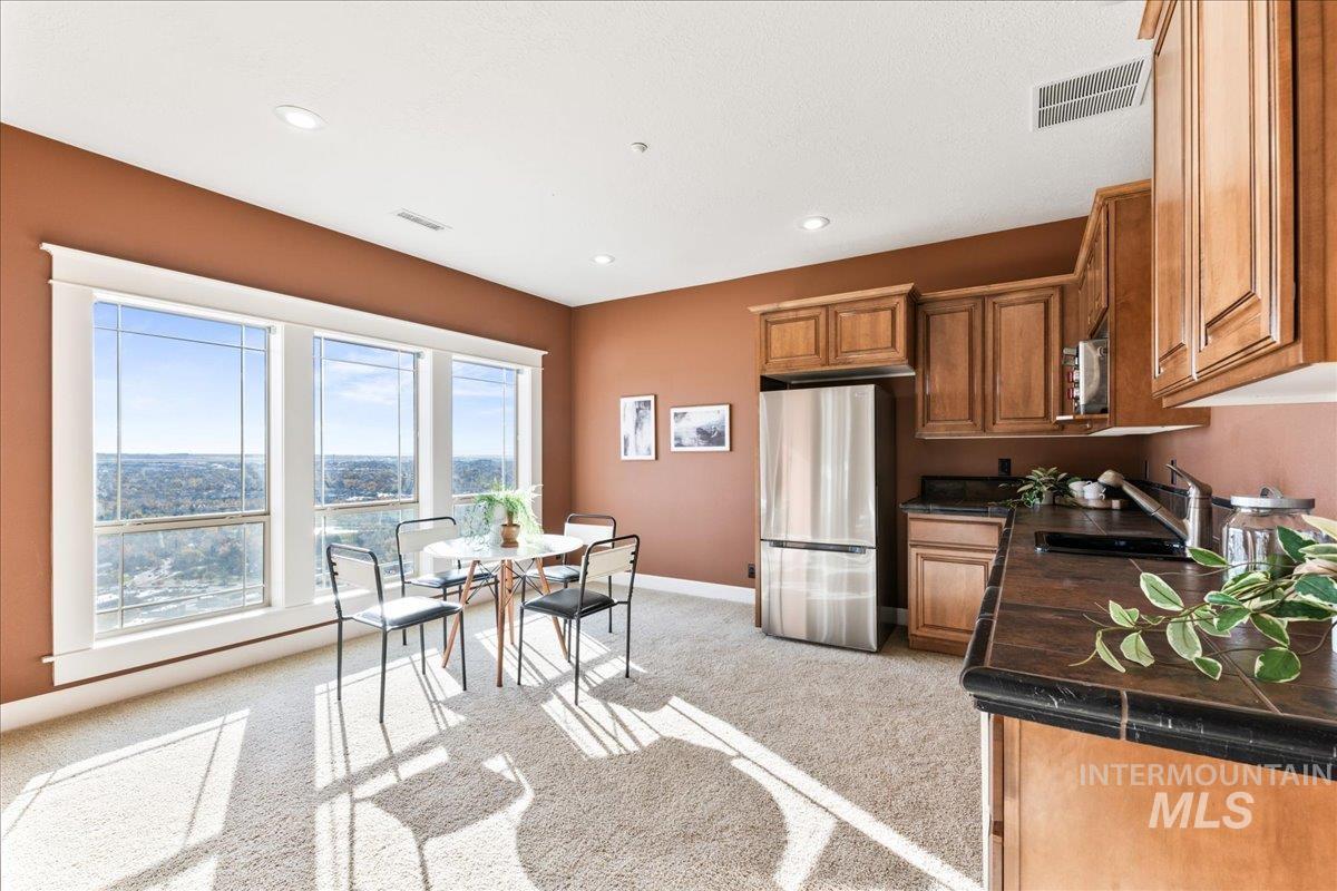 Kitchen featuring freestanding refrigerator, light carpet, recessed lighting, brown cabinetry, and tile counters