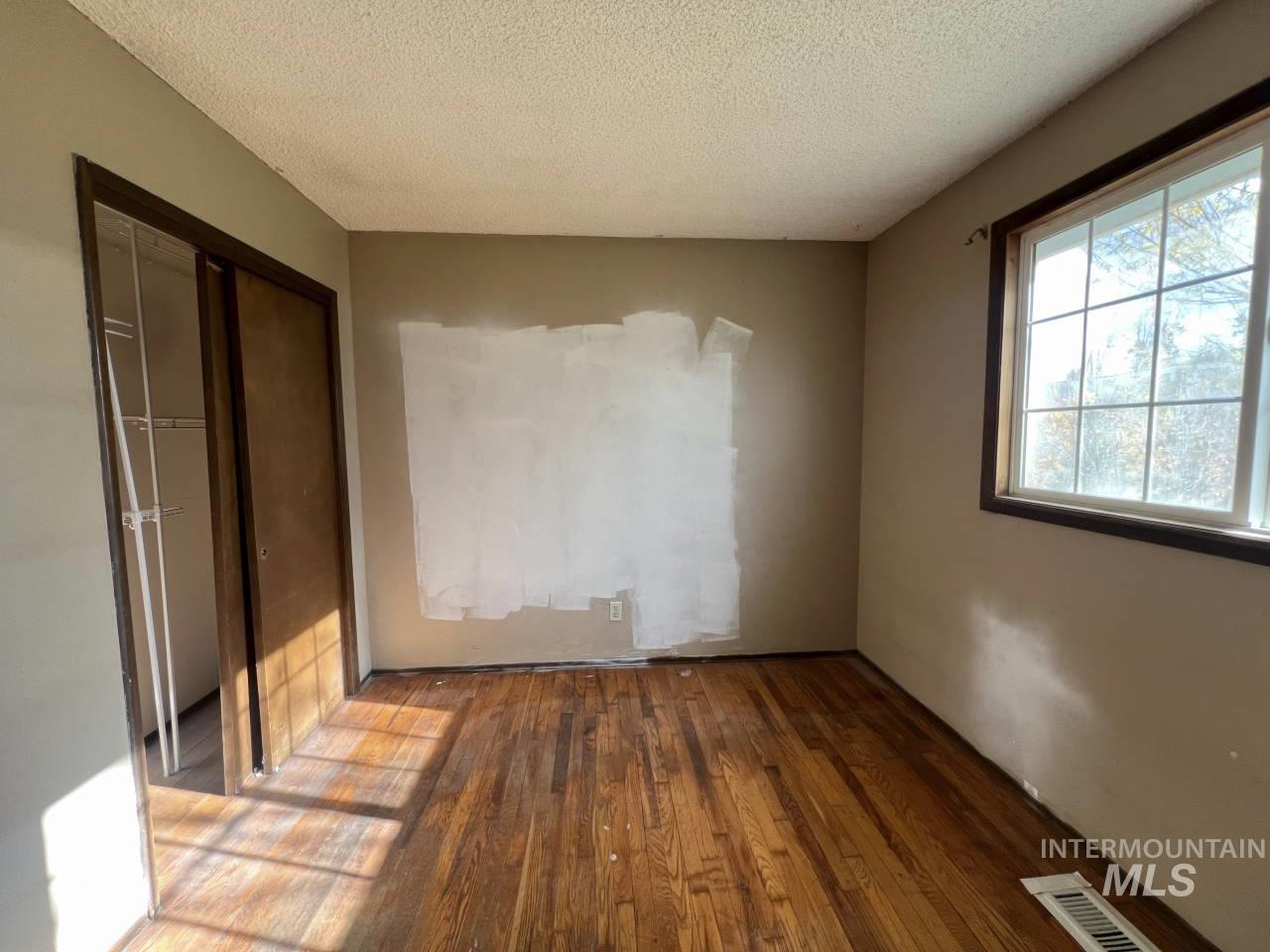 Unfurnished bedroom with hardwood / wood-style floors, a textured ceiling, and a closet