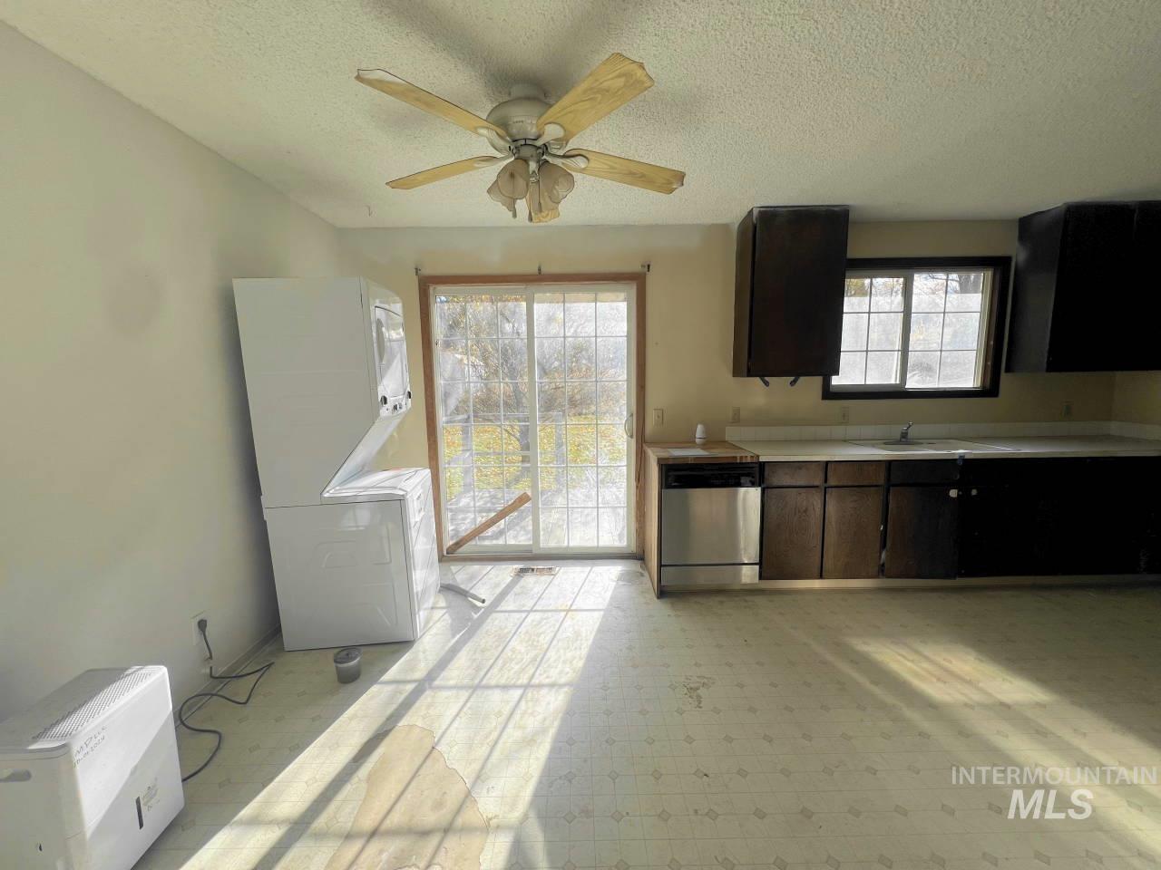 Kitchen with light countertops, stainless steel dishwasher, a textured ceiling, light flooring, and a ceiling fan