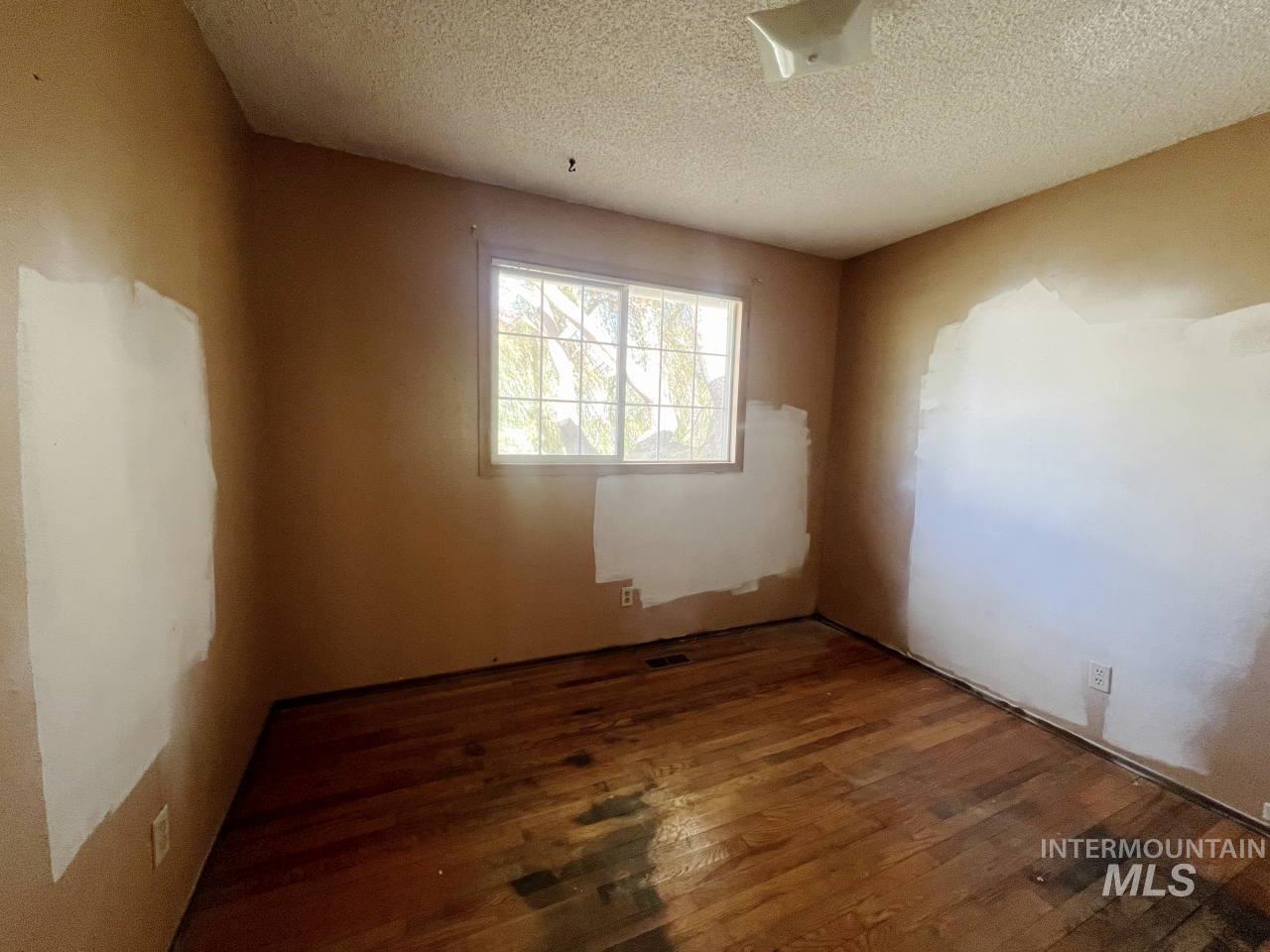 Spare room featuring wood-type flooring and a textured ceiling