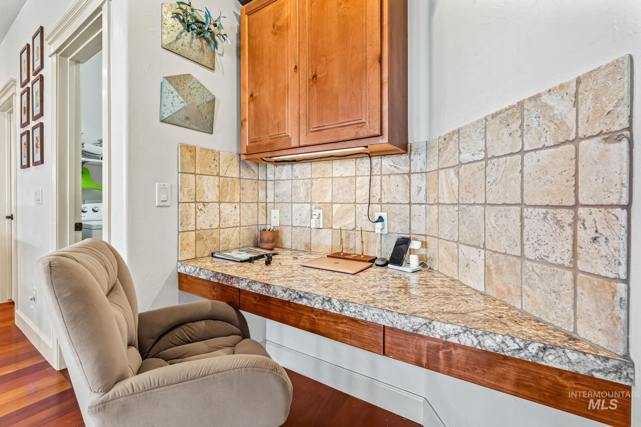 Kitchen featuring wood finished floors, brown cabinetry, decorative backsplash, and washer / dryer