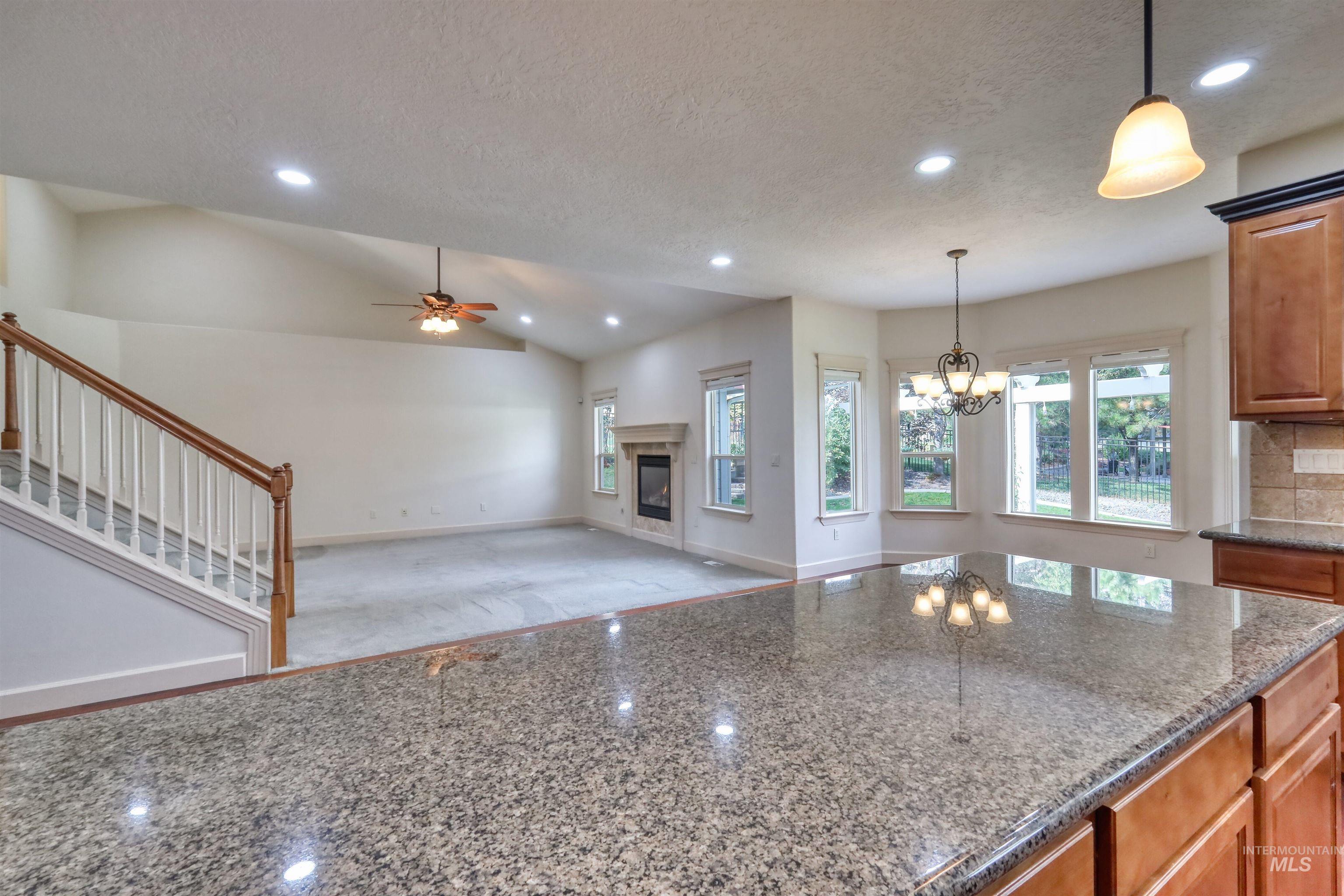 Kitchen with dark stone counters, recessed lighting, decorative light fixtures, brown cabinets, and a glass covered fireplace