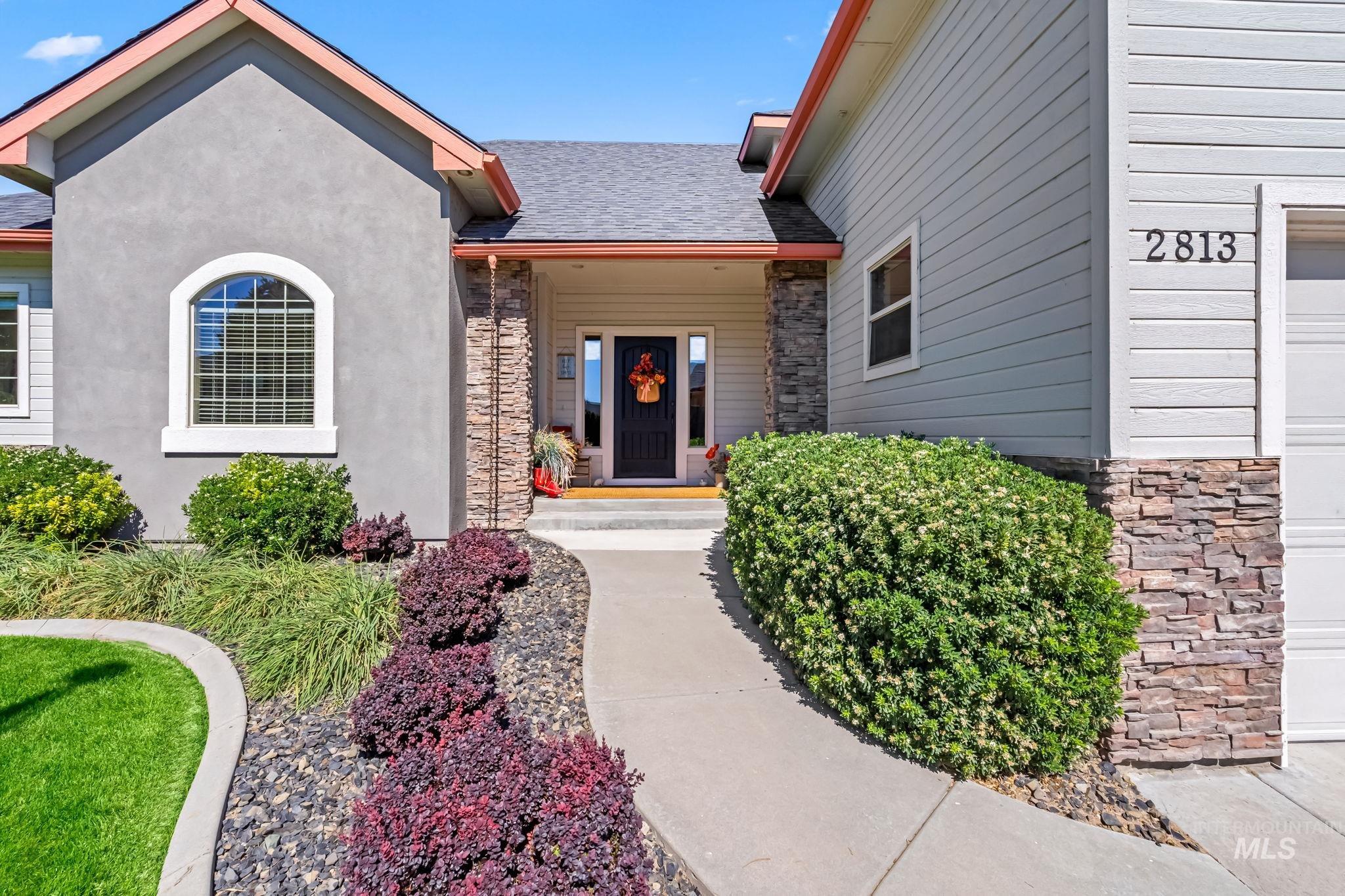 Property entrance featuring stone siding, roof with shingles, and stucco siding