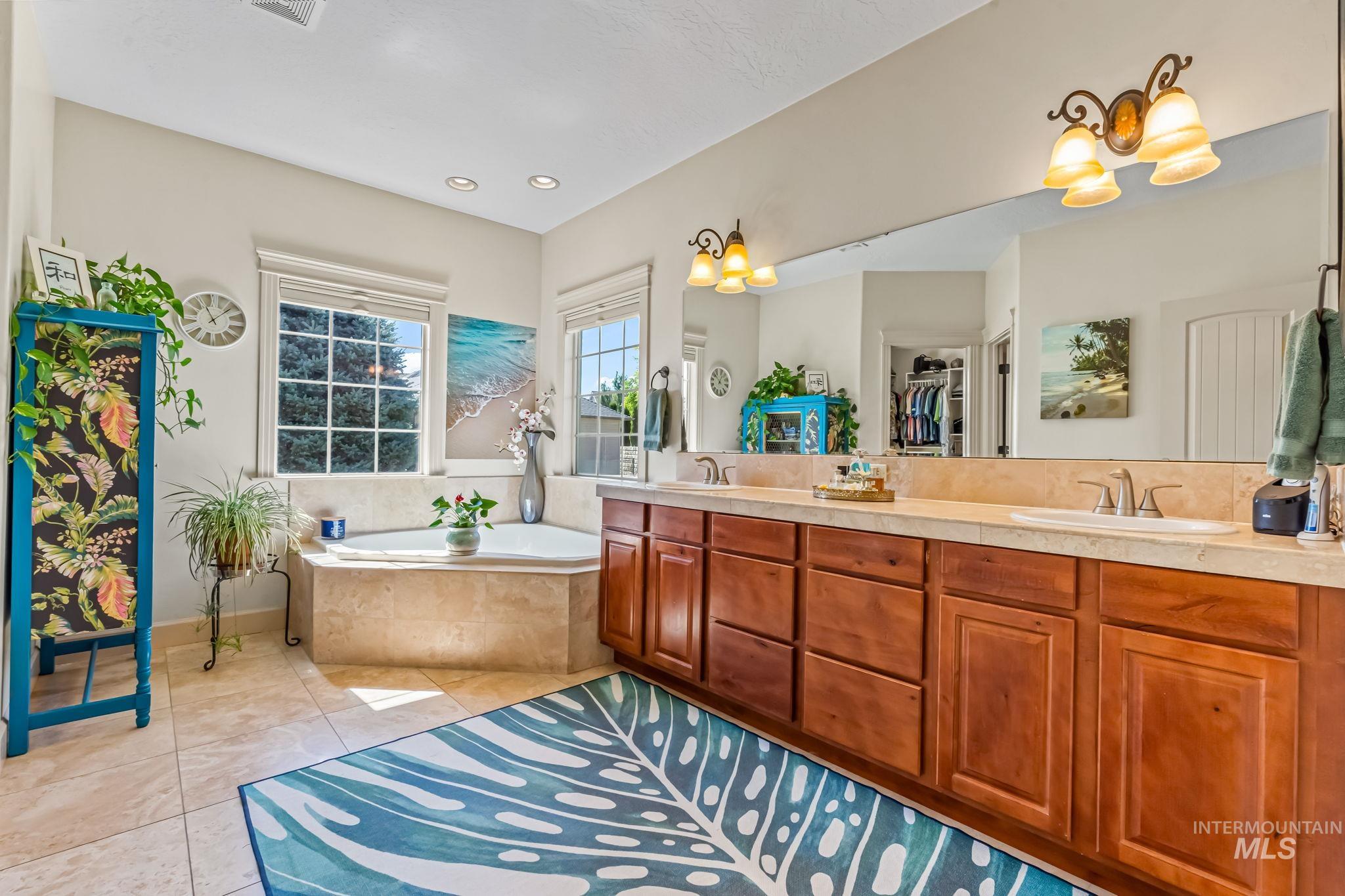 Full bath with double vanity, a bath, and tile patterned flooring