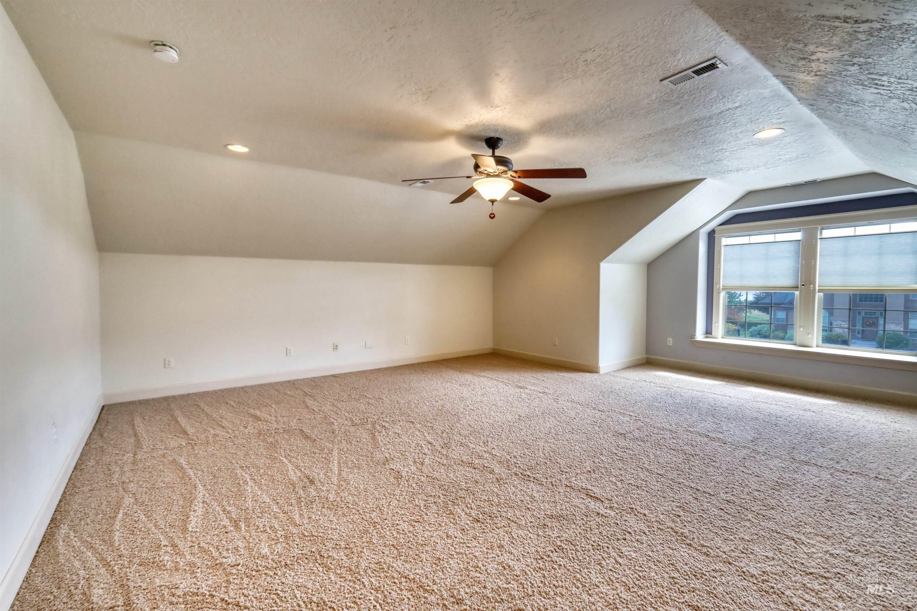 Bonus room featuring vaulted ceiling, light colored carpet, a textured ceiling, a ceiling fan, and recessed lighting