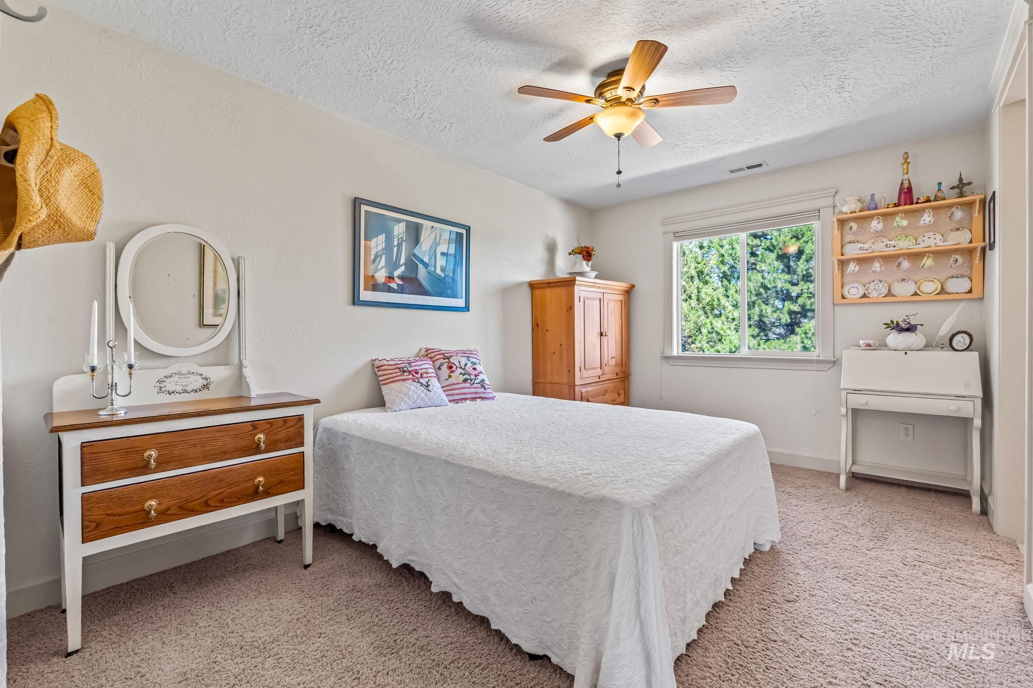 Bedroom featuring a textured ceiling, light carpet, and ceiling fan