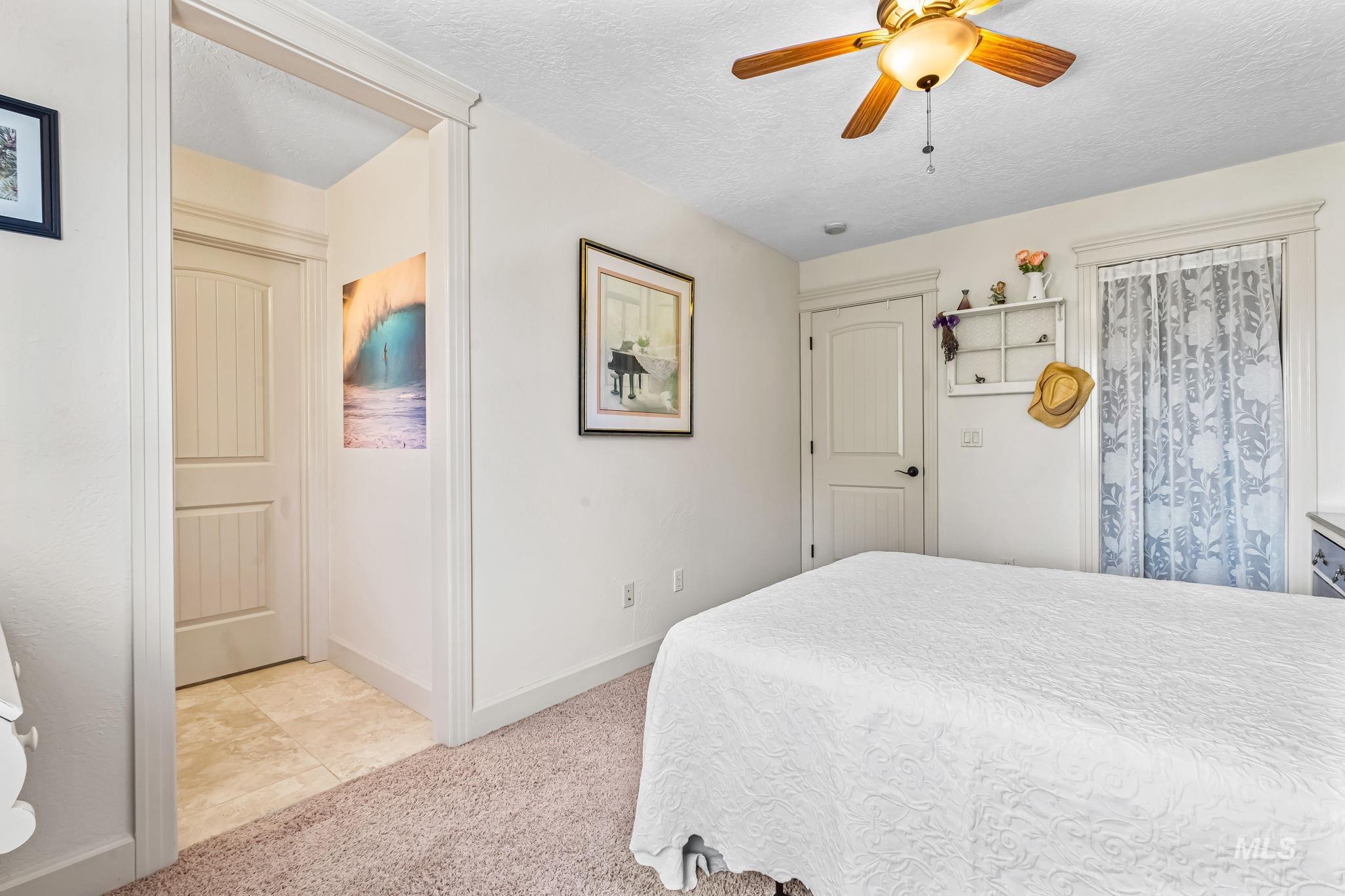 Bedroom featuring light carpet, a textured ceiling, and a ceiling fan