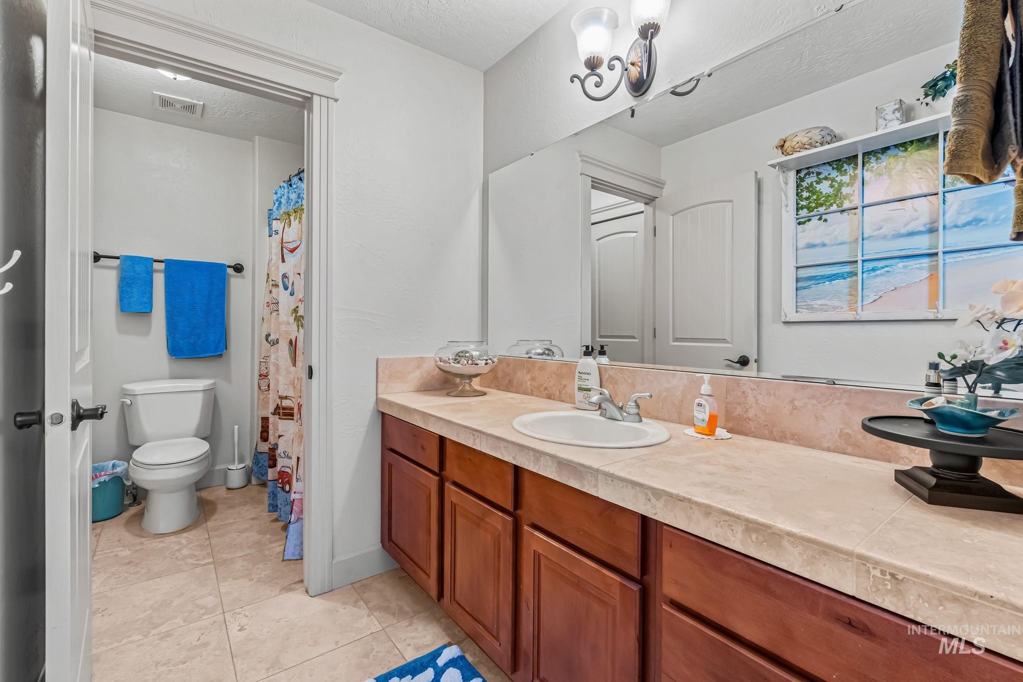 Bathroom with vanity, tile patterned floors, and a textured ceiling