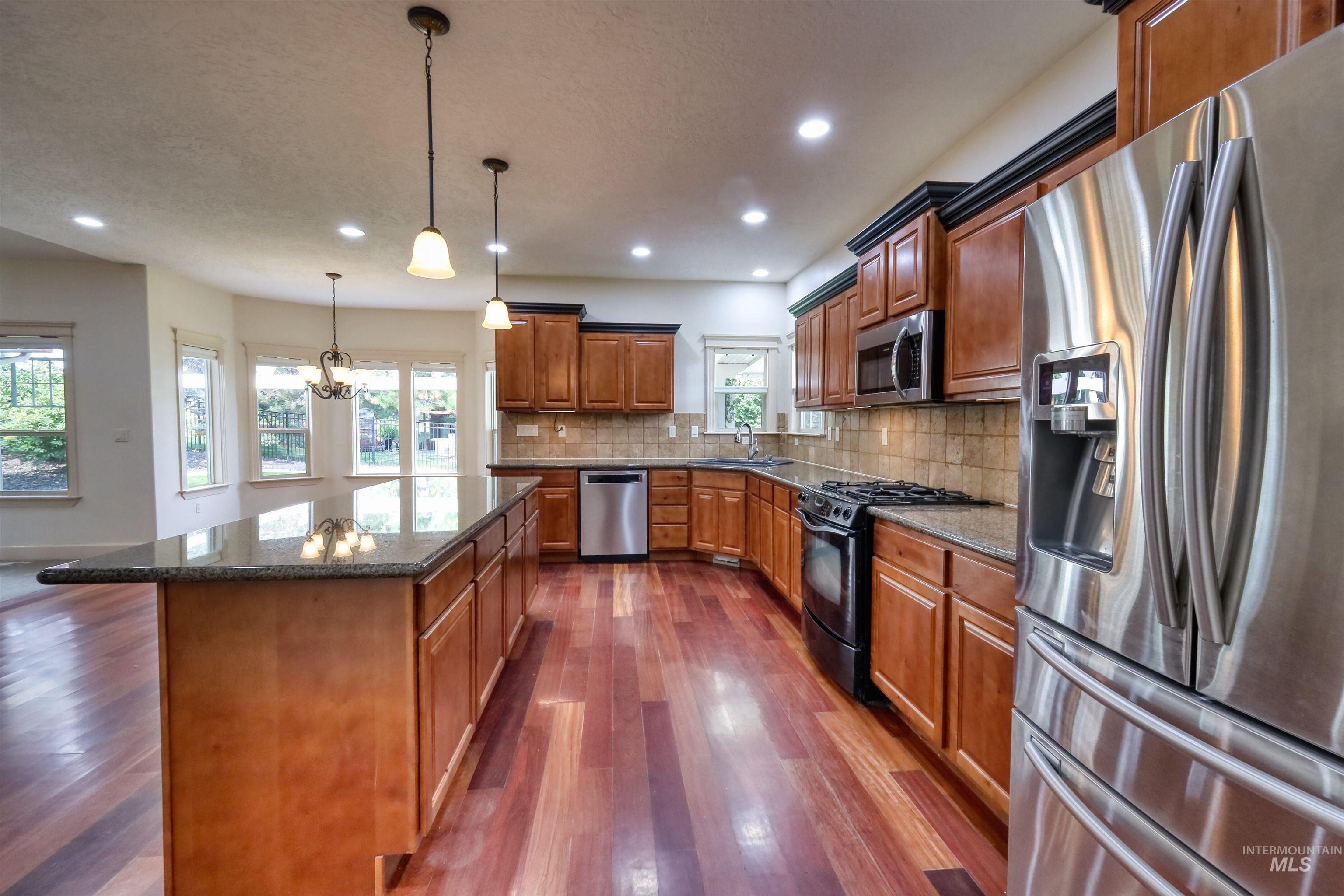 Kitchen with stainless steel appliances, dark stone counters, tasteful backsplash, decorative light fixtures, and recessed lighting