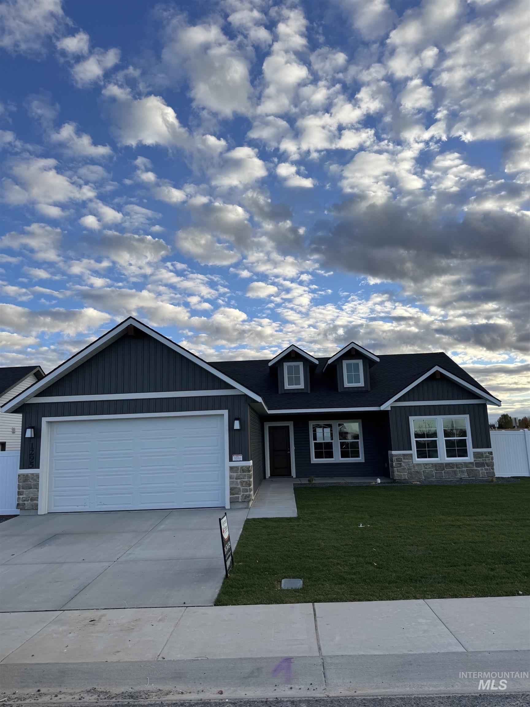 Craftsman-style house with stone siding, driveway, an attached garage, and board and batten siding