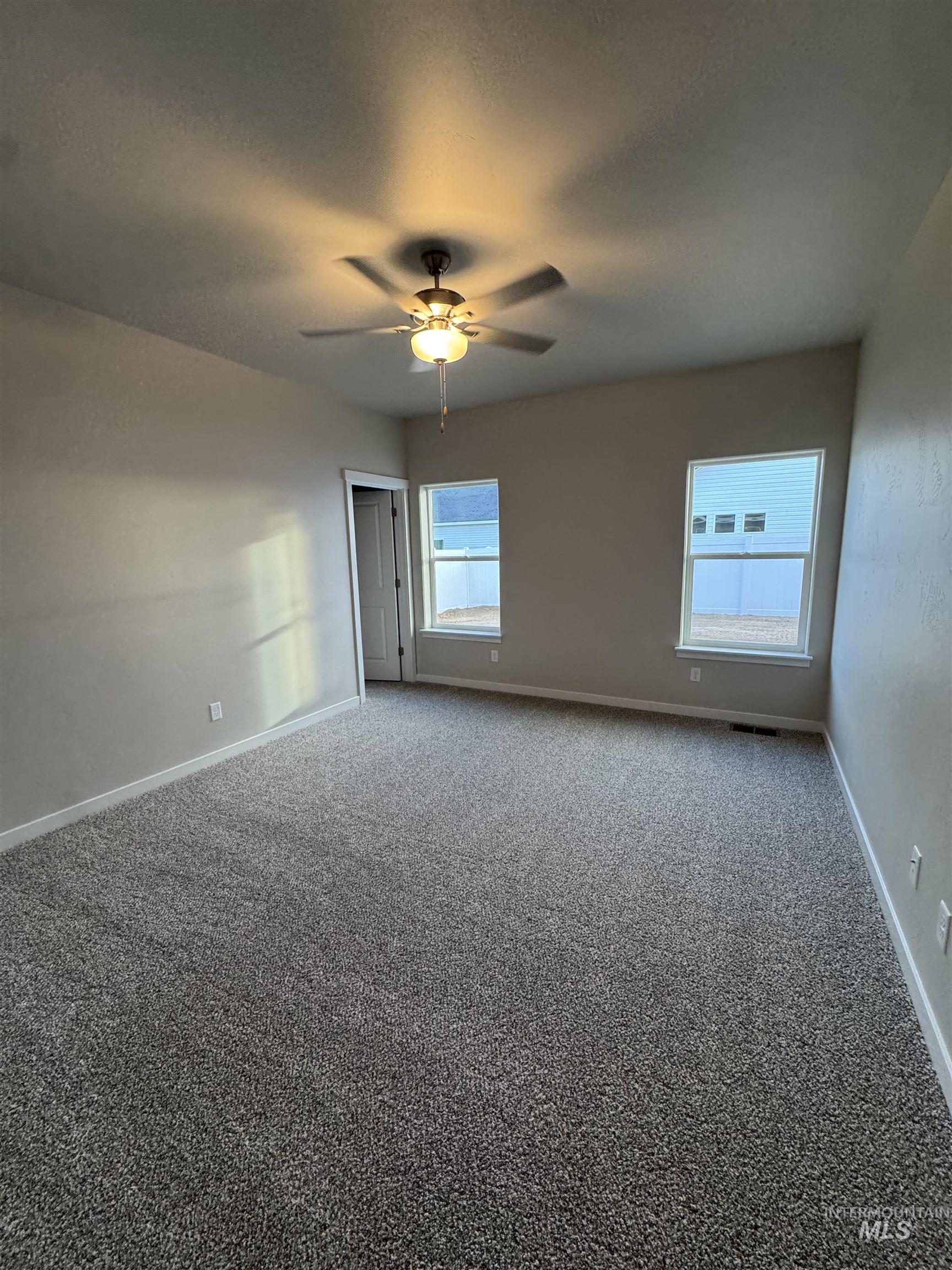 Carpeted empty room with baseboards and ceiling fan