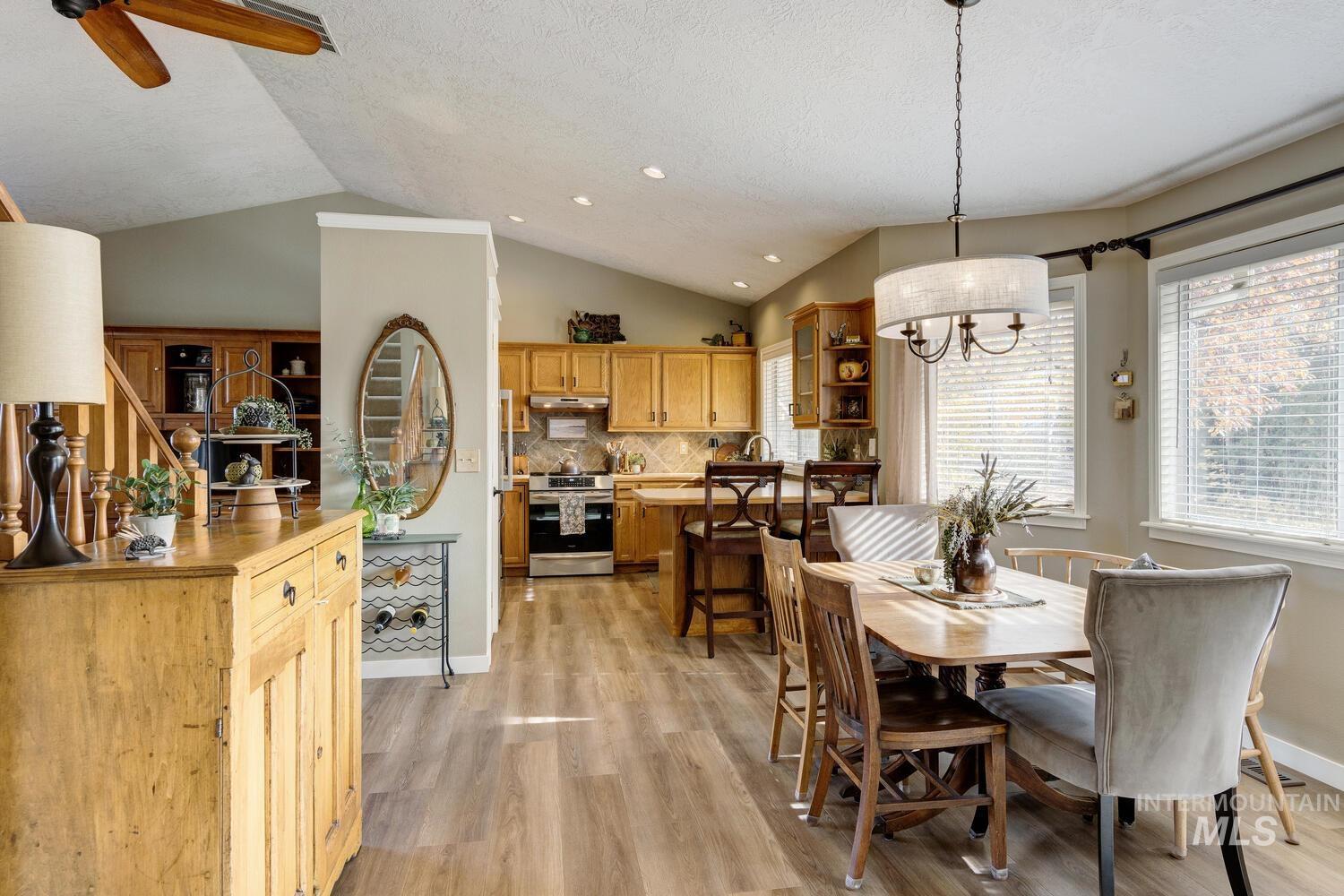 Dining area with lofted ceiling, light wood-style flooring, recessed lighting, a textured ceiling, and a chandelier