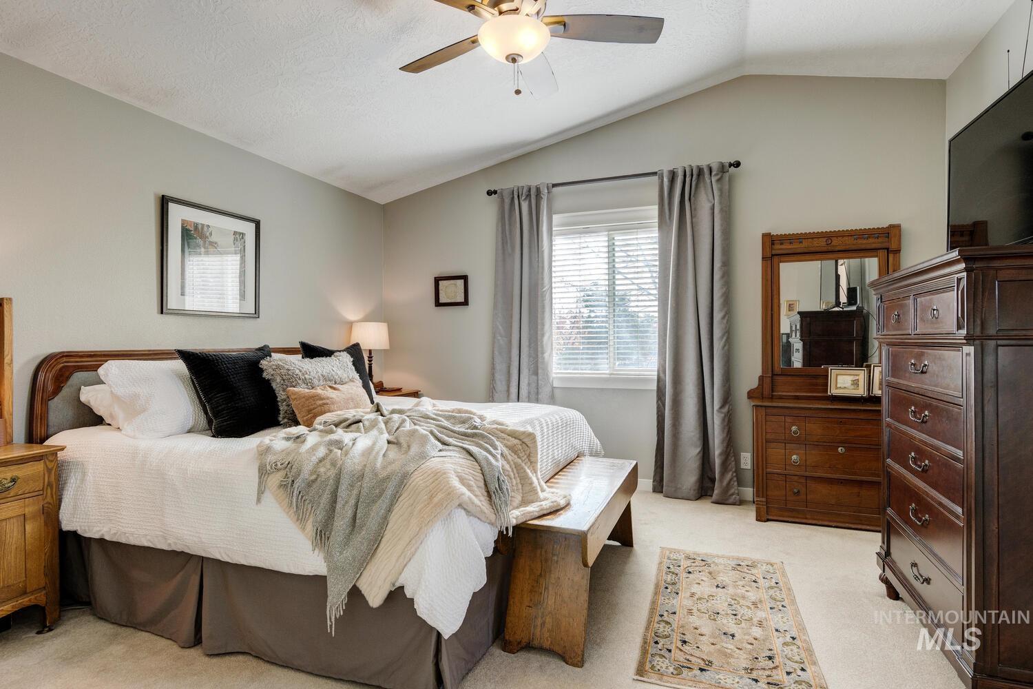 Bedroom with light colored carpet, vaulted ceiling, and a ceiling fan