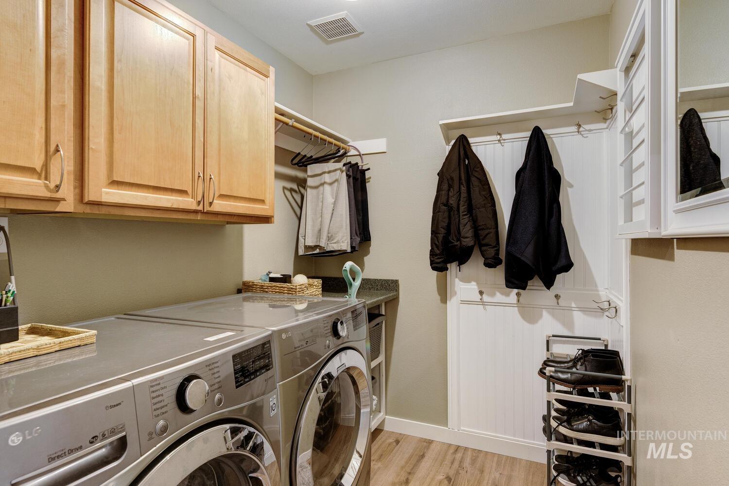 Laundry room with light wood finished floors, independent washer and dryer, and cabinet space
