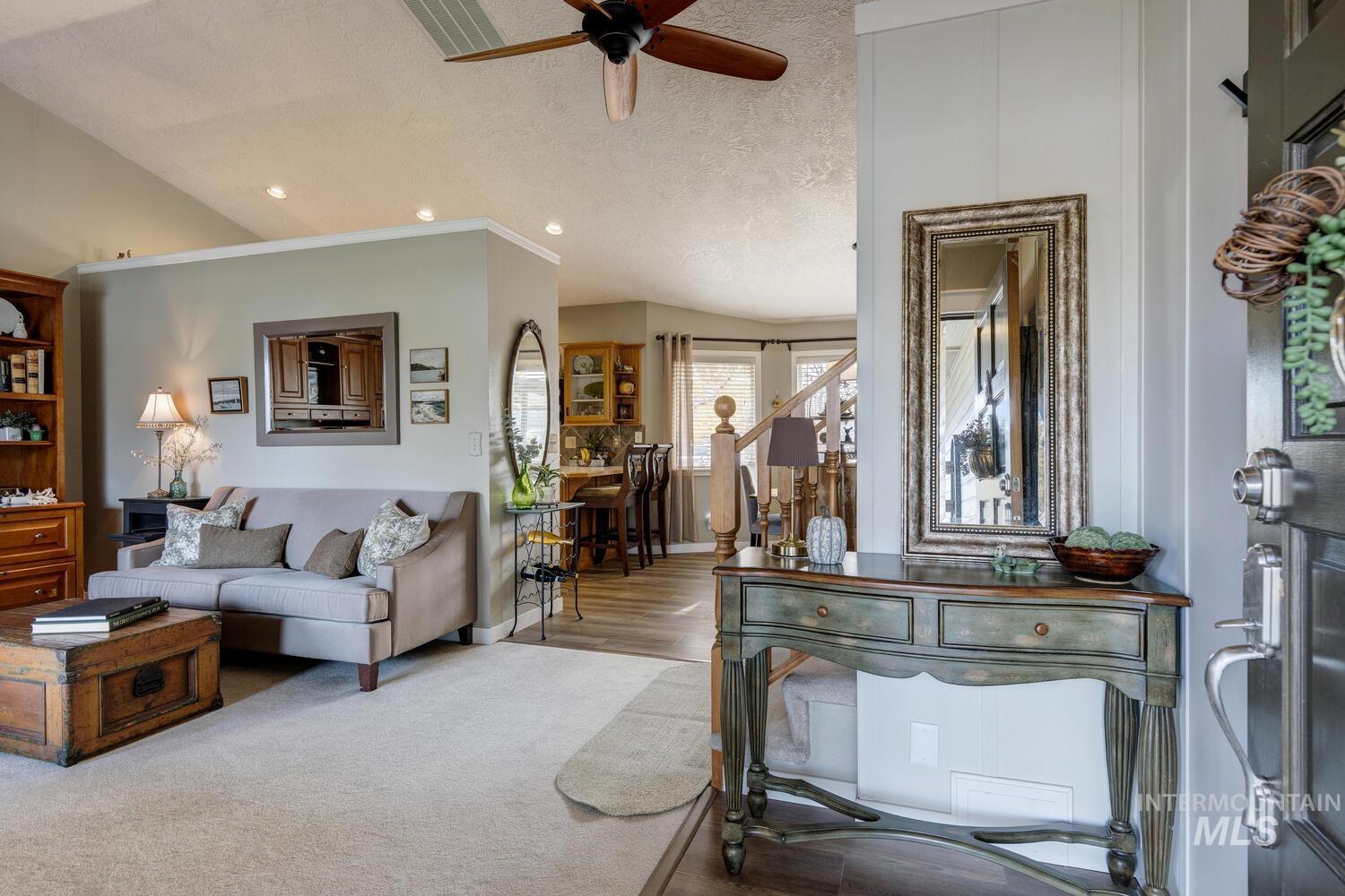 Living room featuring lofted ceiling, a textured ceiling, a ceiling fan