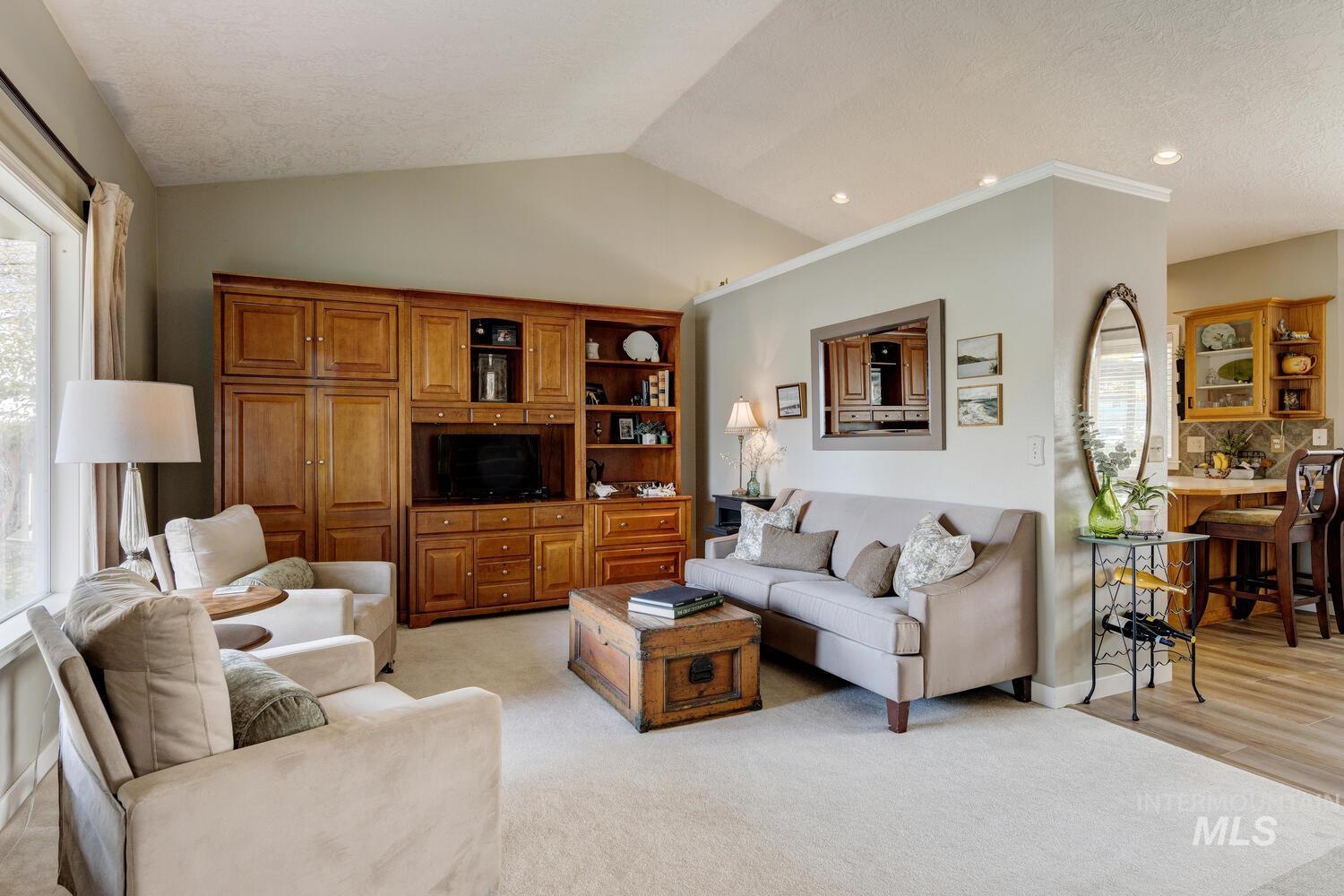 Living area with lofted ceiling, light colored carpet