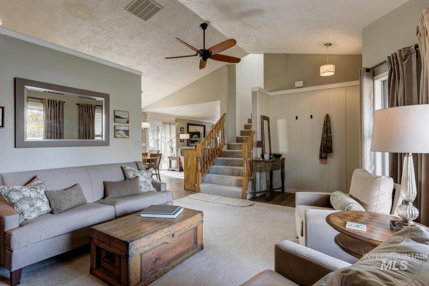Living room featuring healthy amount of natural light, a ceiling fan, a textured ceiling, stairway