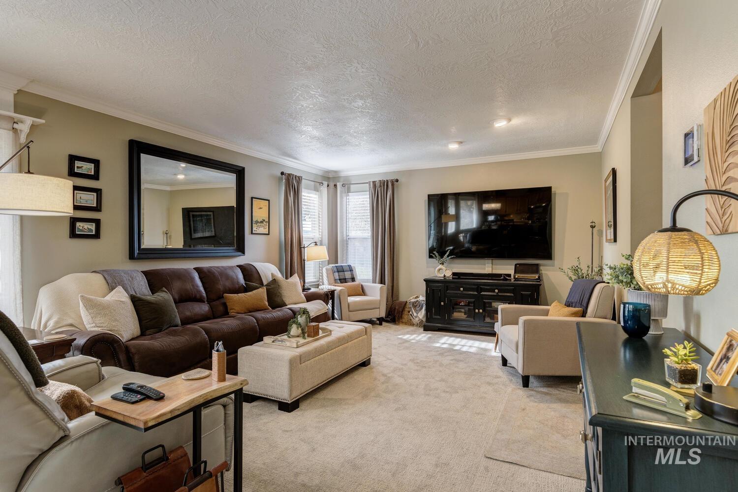 Living area with ornamental molding, light colored carpet, and a textured ceiling