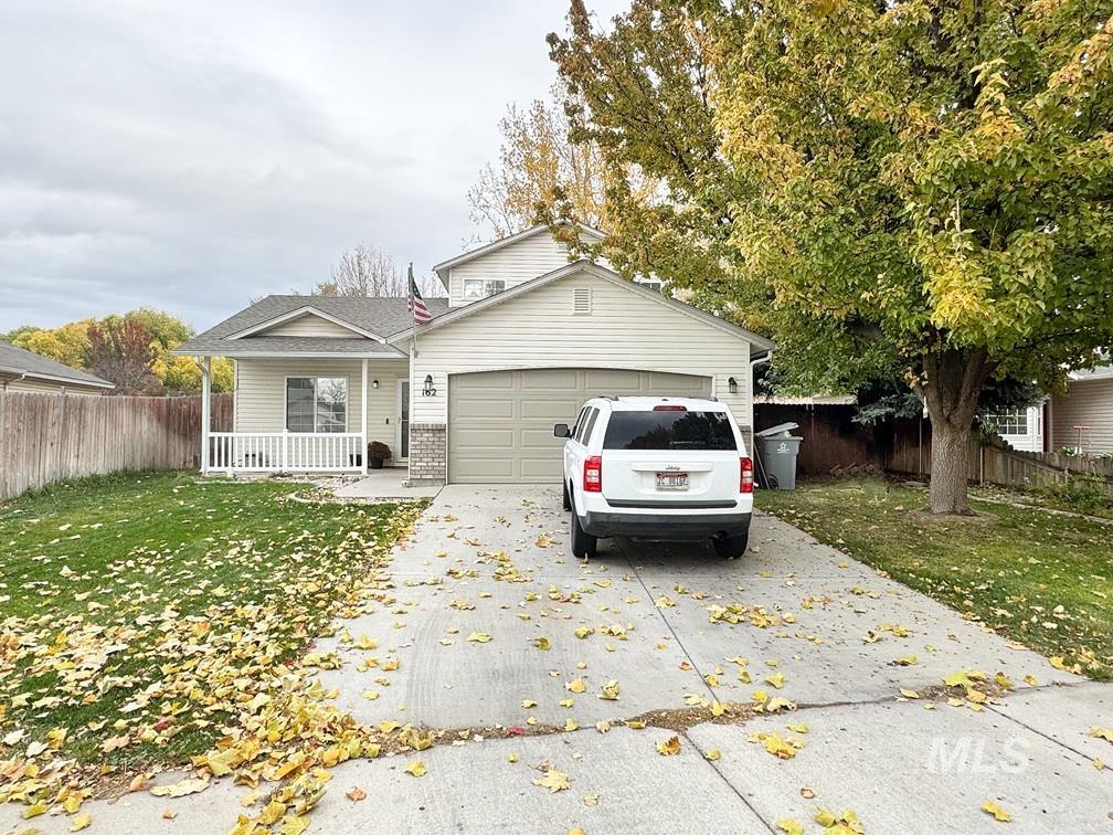 View of front facade featuring concrete driveway, a garage, covered porch, and brick siding