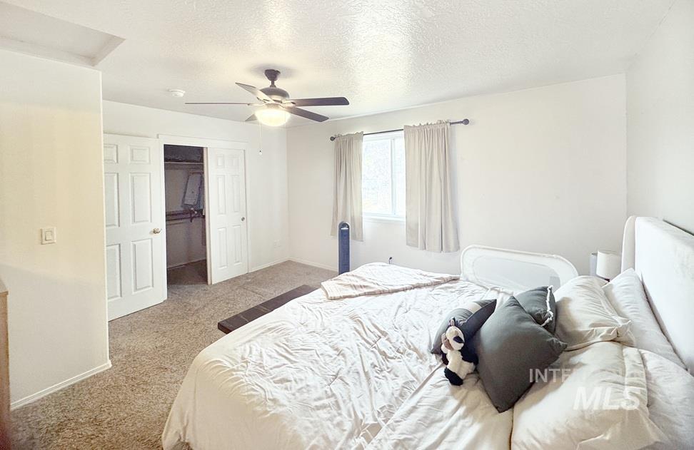 Carpeted bedroom with a textured ceiling and a ceiling fan