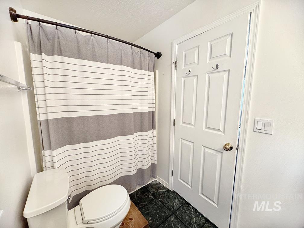 Full bathroom with a shower with shower curtain and a textured ceiling