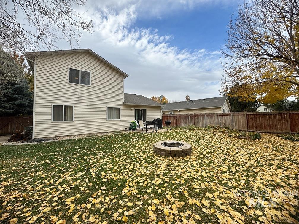 Rear view of property featuring a patio area, a fenced backyard, and a fire pit