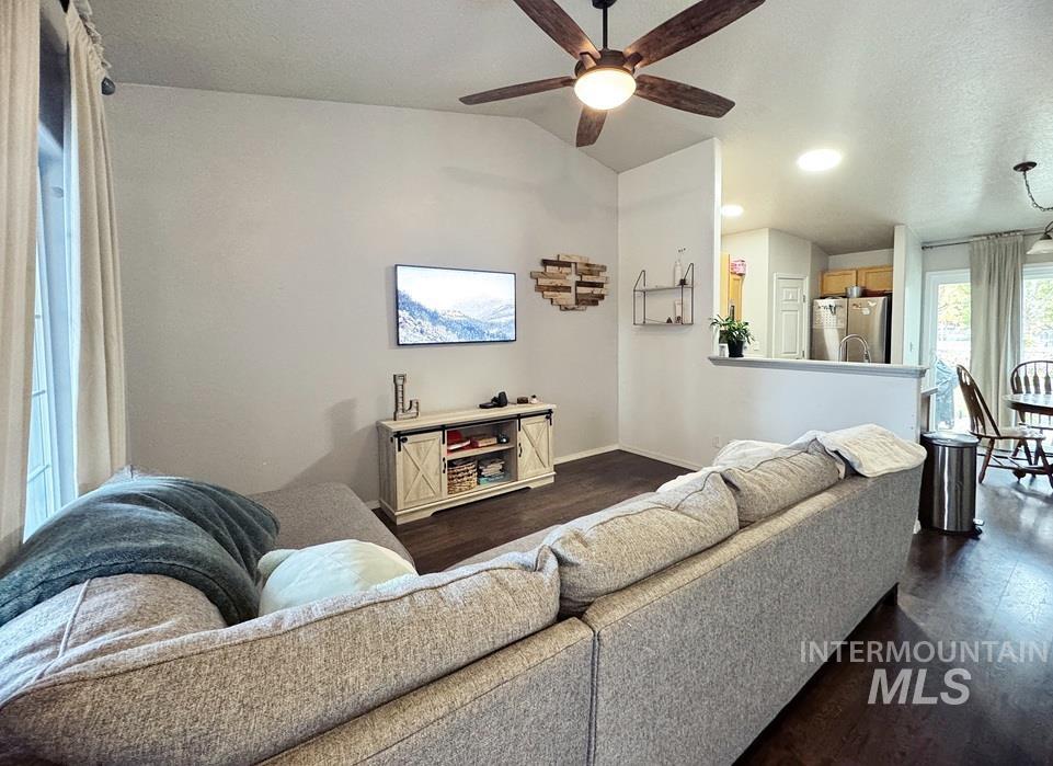 Living area with vaulted ceiling, dark wood-style flooring, a textured ceiling, ceiling fan, and recessed lighting