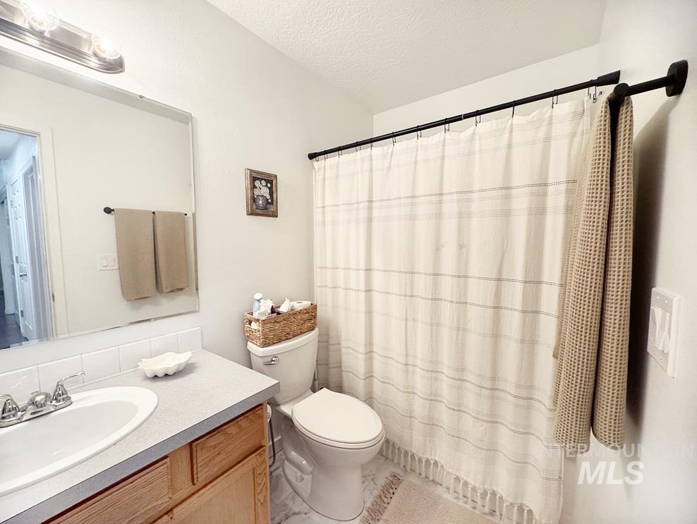 Full bathroom with a textured ceiling, a shower with shower curtain, and vanity