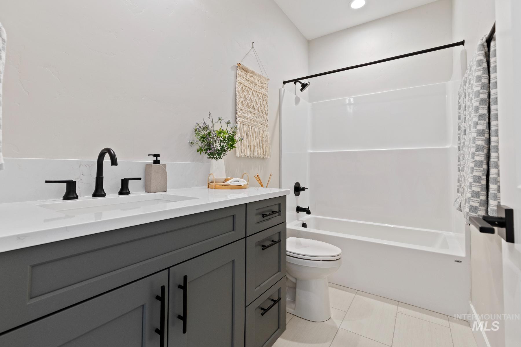 Full bath with shower / bath combo with shower curtain, vanity, and light tile patterned floors