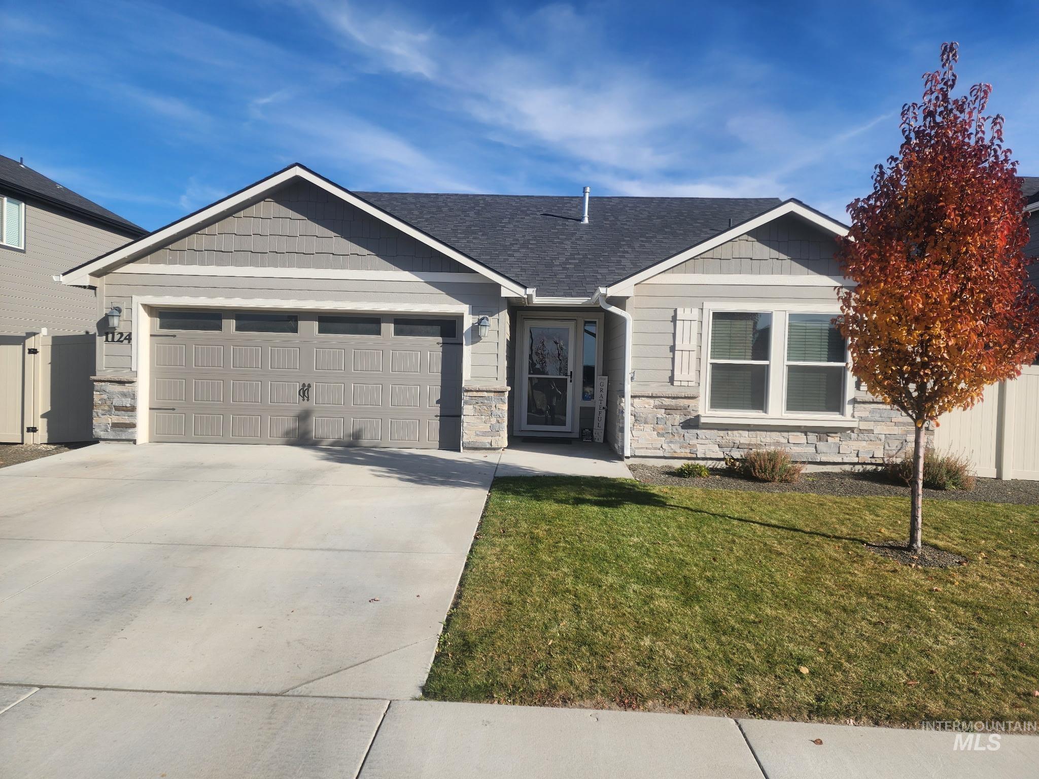 View of front facade featuring stone siding, driveway, a garage, and a shingled roof