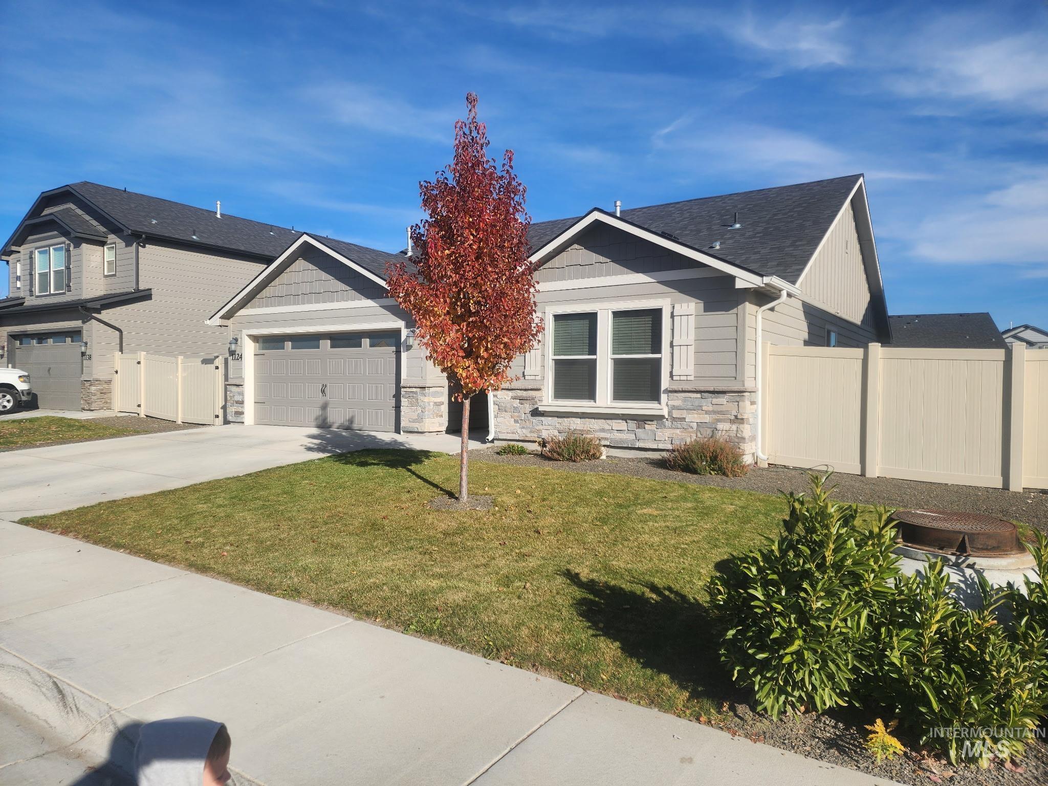 View of front of home with stone siding, driveway, roof with shingles, and a garage