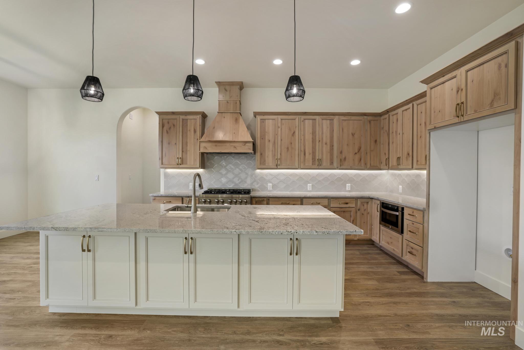 Kitchen featuring tasteful backsplash, decorative light fixtures, dark wood finished floors, light stone countertops, and recessed lighting