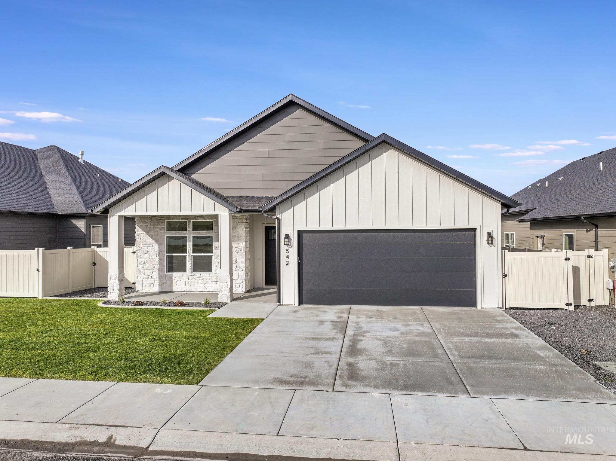 Modern inspired farmhouse featuring a gate, board and batten siding, an attached garage, and driveway