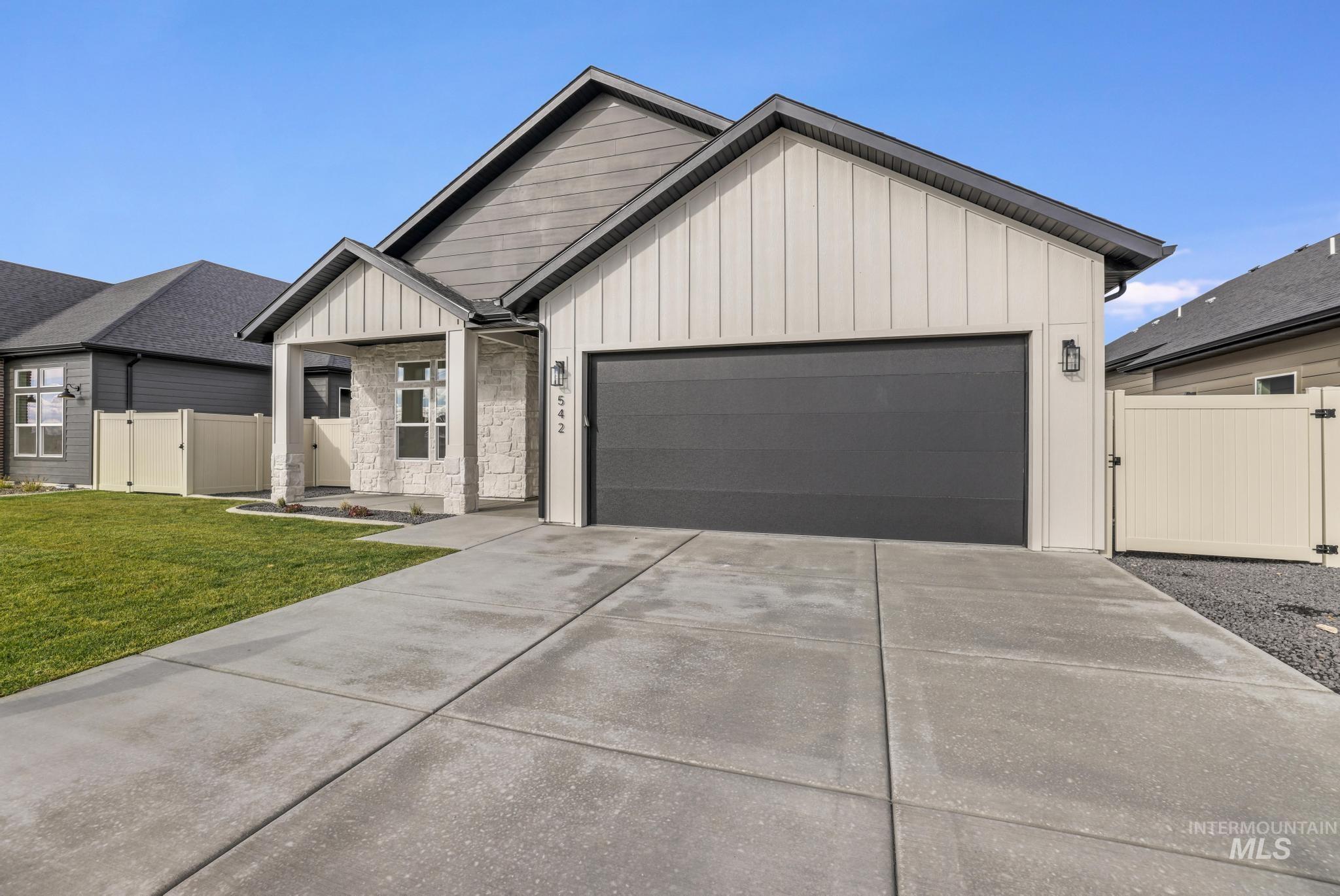 View of front of house with board and batten siding, a gate, a garage, and concrete driveway