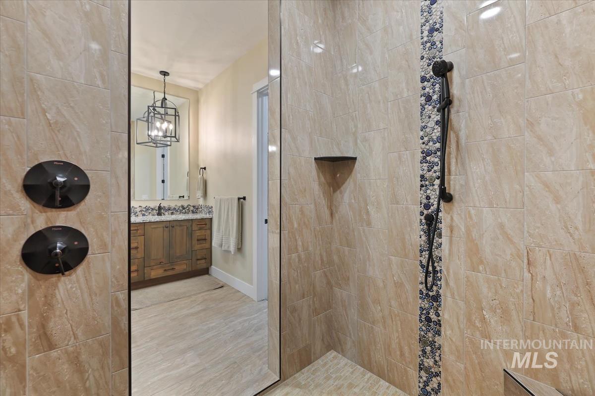 Full bath with walk in shower, vanity, and a chandelier
