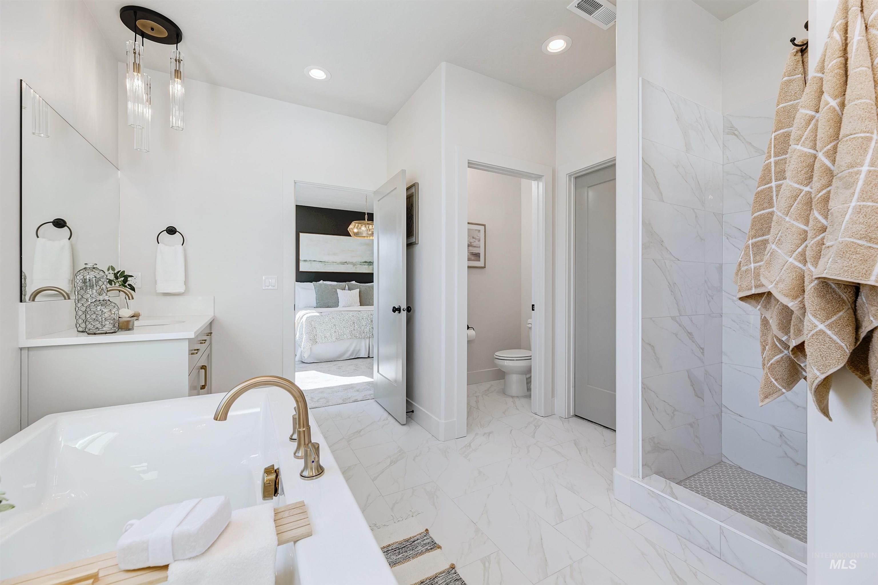 Ensuite bathroom featuring vanity, a freestanding bath, recessed lighting, light marble finish flooring, and a marble finish shower