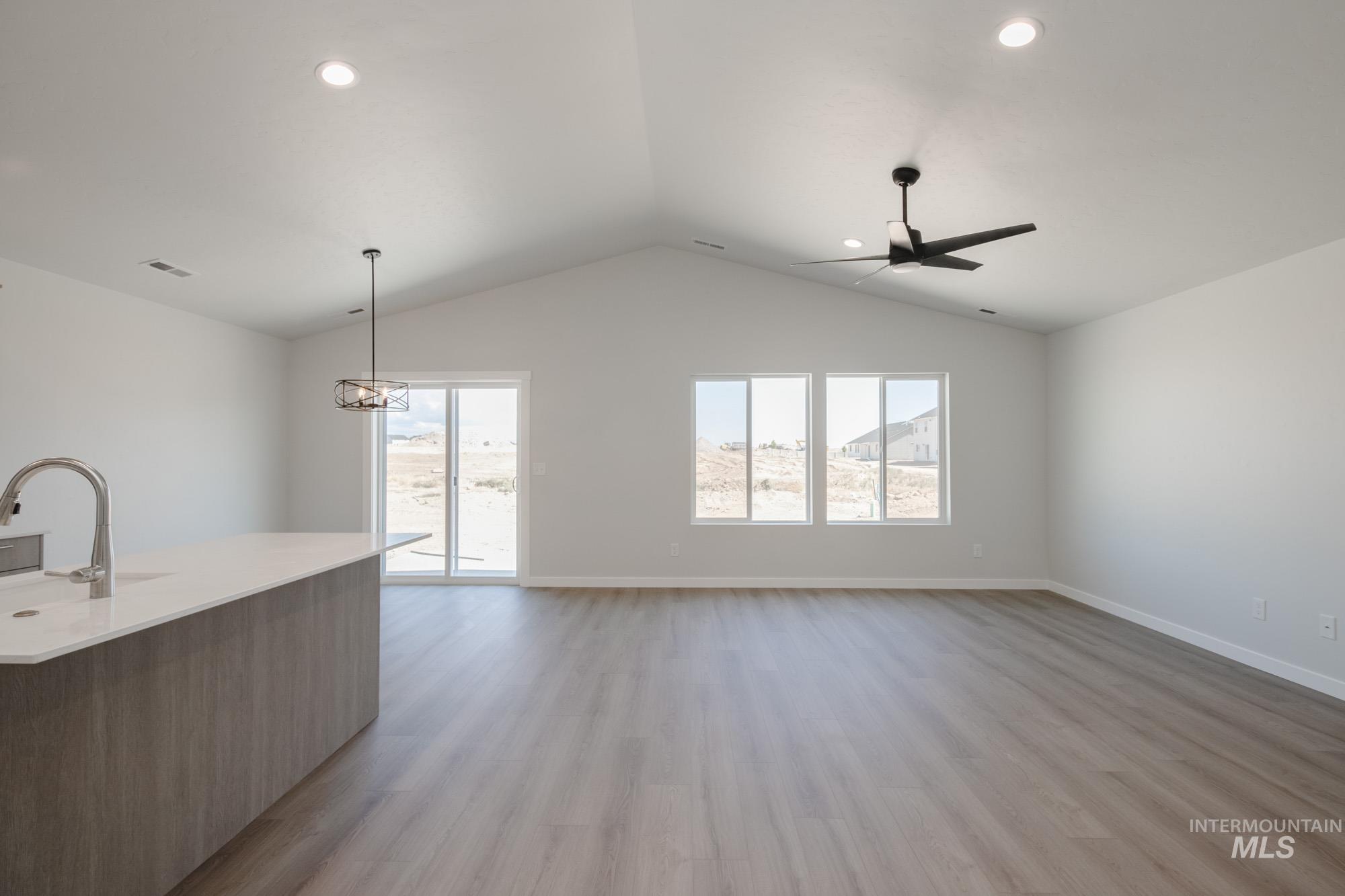 Unfurnished living room featuring light wood finished floors, lofted ceiling, recessed lighting, a chandelier, and ceiling fan