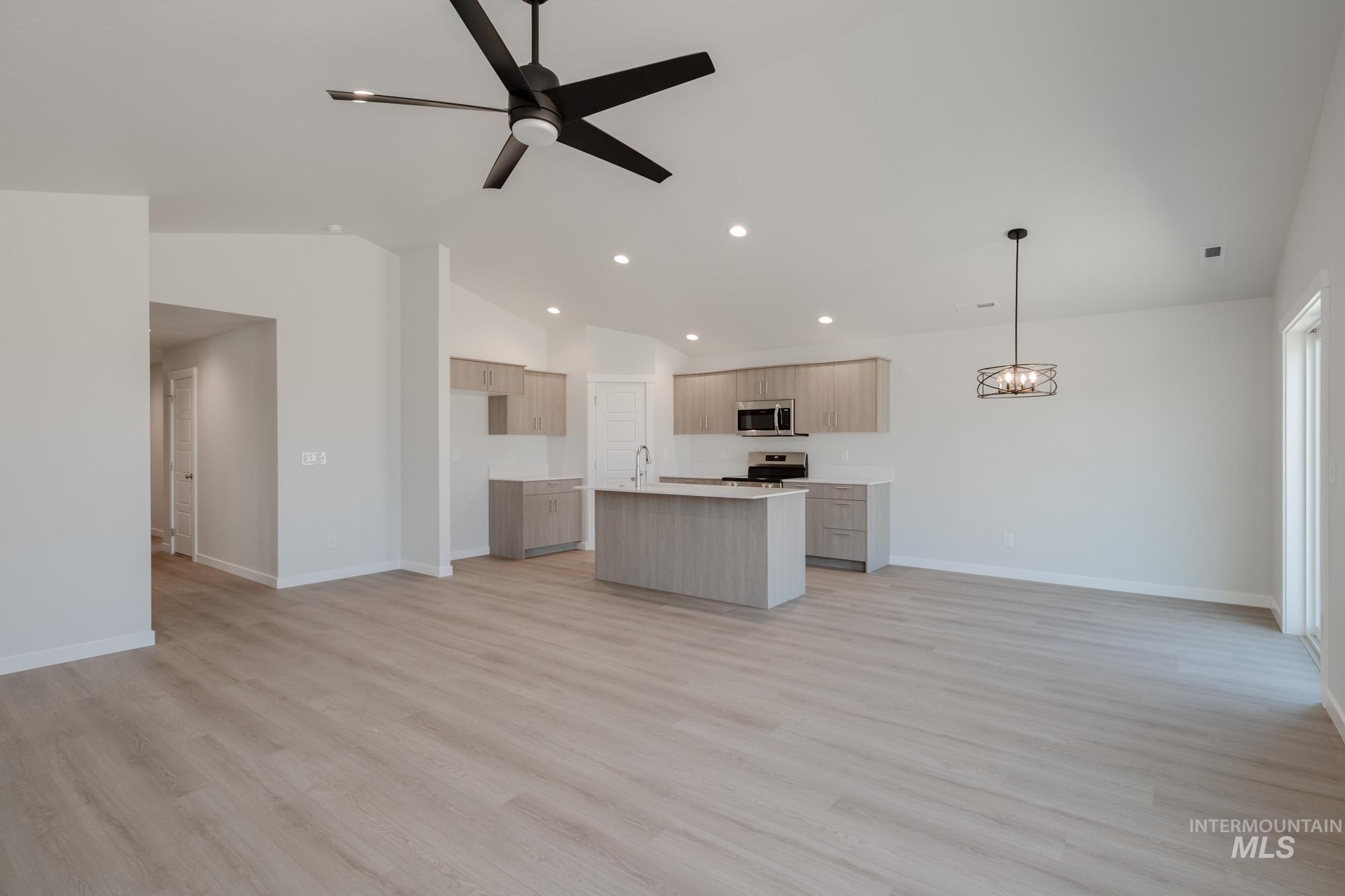 Unfurnished living room with light wood-type flooring, vaulted ceiling, a ceiling fan, and recessed lighting