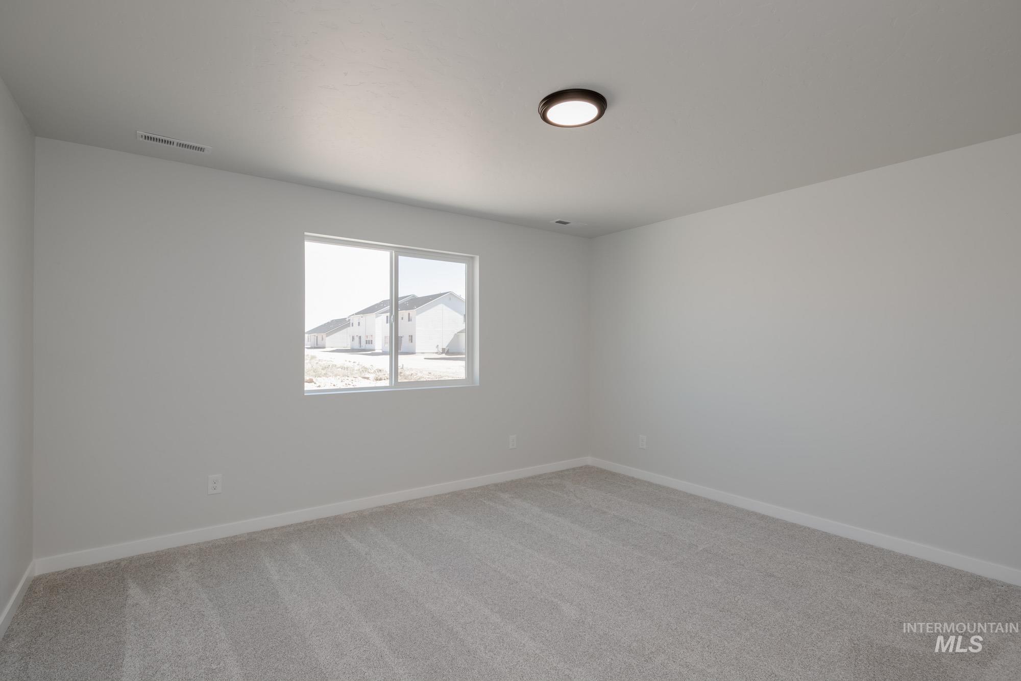 Empty room featuring light colored carpet and baseboards