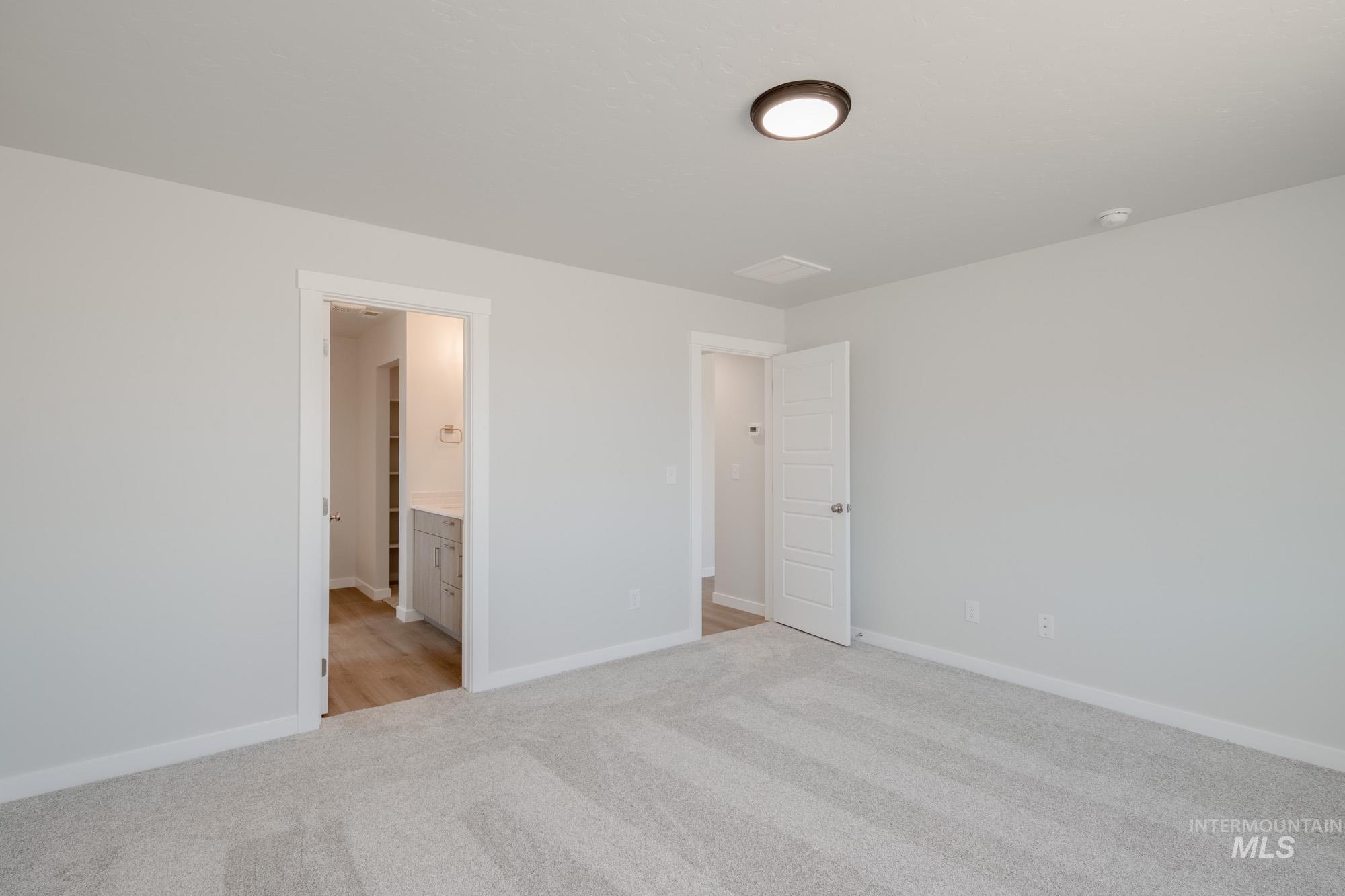 Unfurnished bedroom featuring light colored carpet and ensuite bath