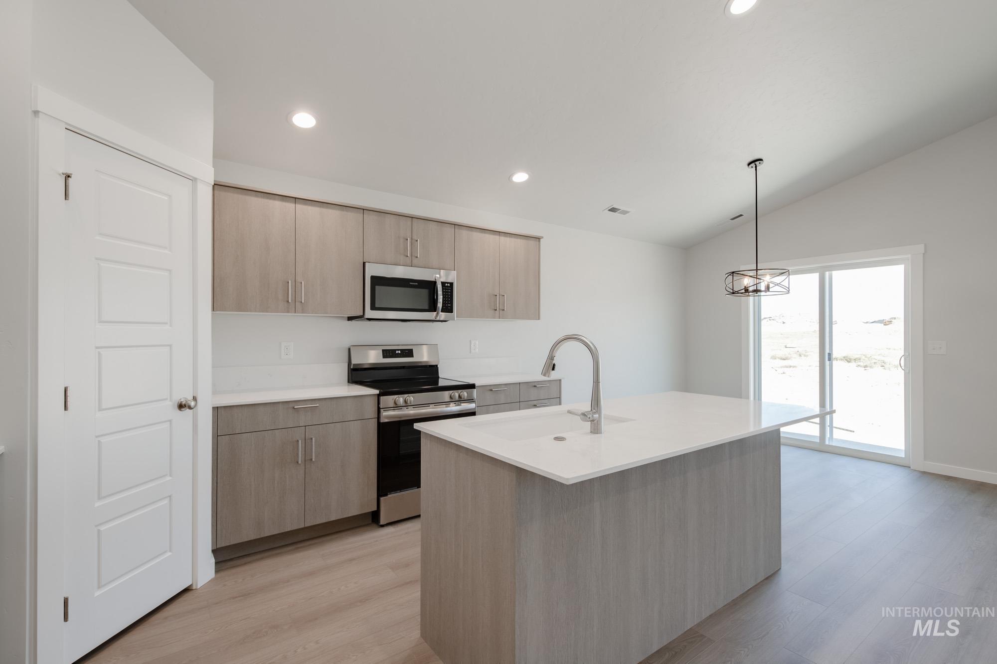Kitchen featuring stainless steel appliances, light brown cabinetry, pendant lighting, light wood finished floors, and recessed lighting