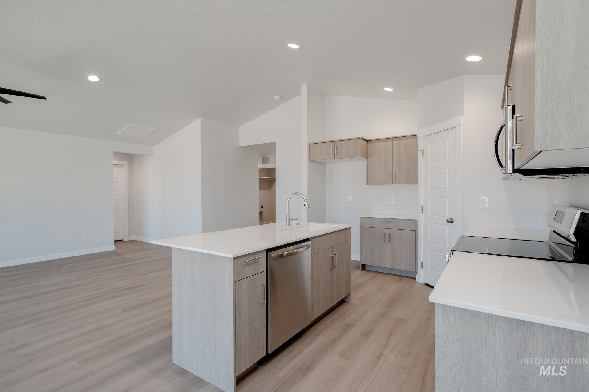 Kitchen featuring recessed lighting, light brown cabinetry, light stone counters, light wood-style flooring, and stainless steel appliances