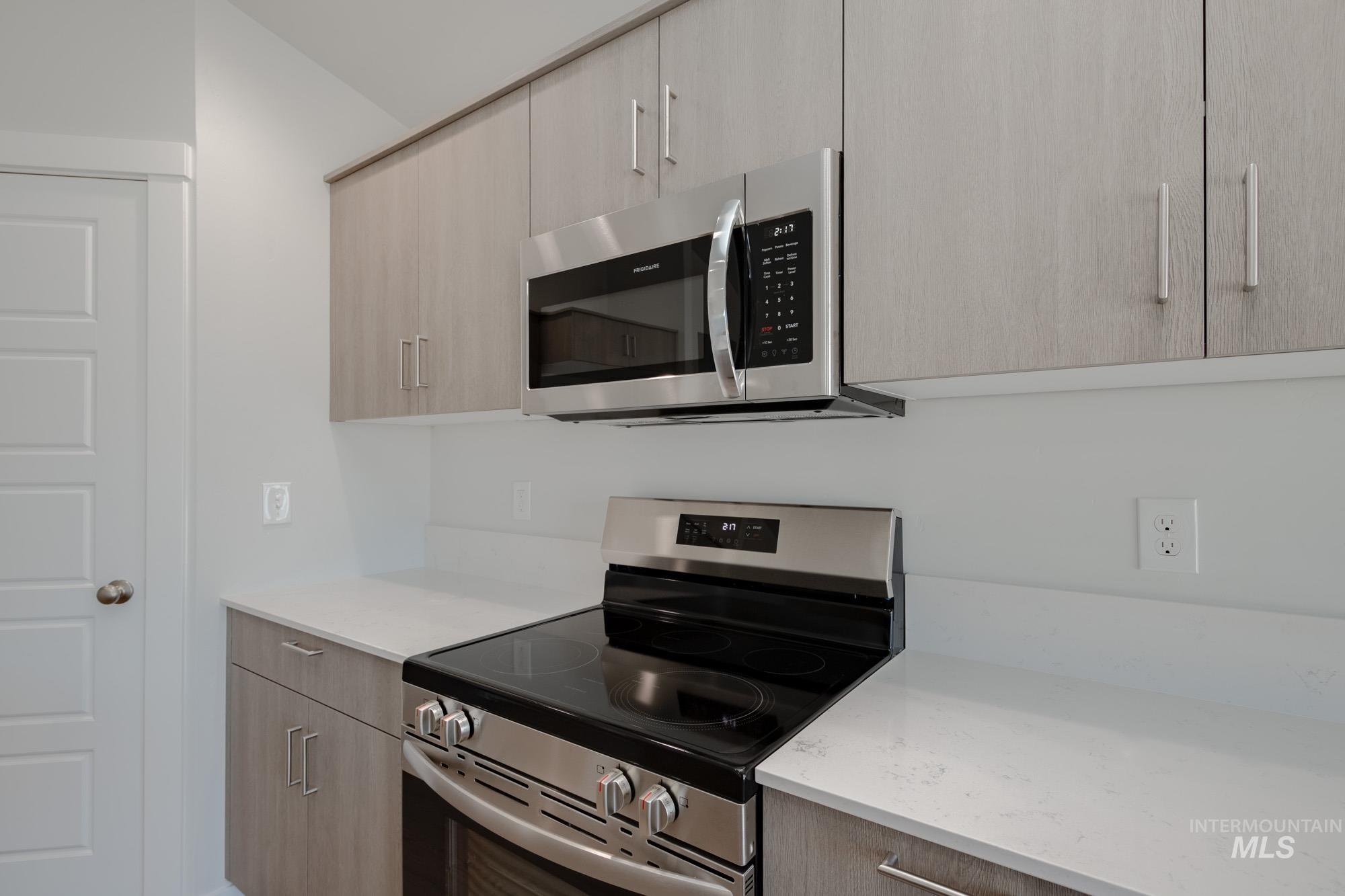 Kitchen featuring appliances with stainless steel finishes, modern cabinets, light stone counters, and light brown cabinetry