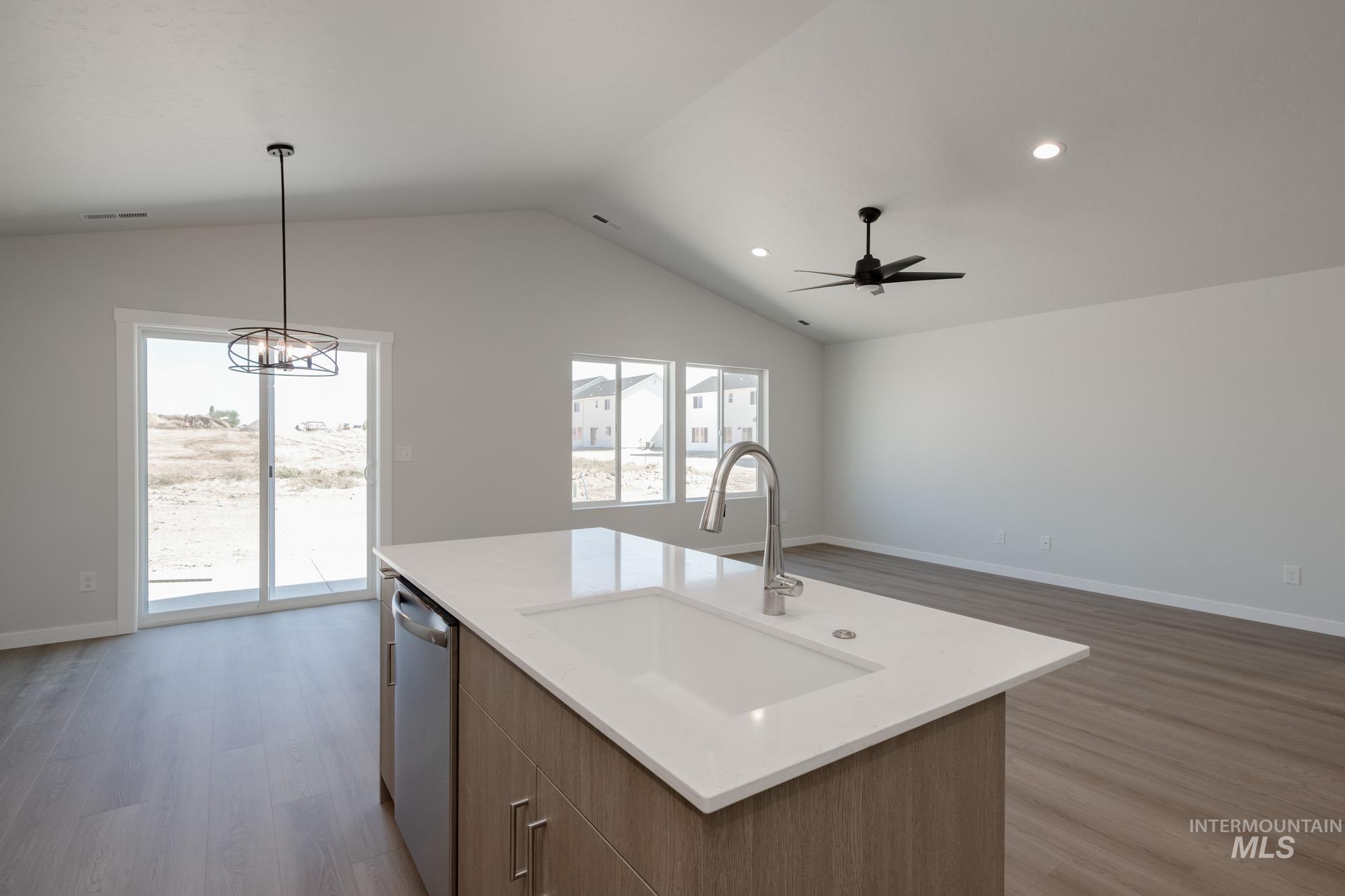 Kitchen with brown cabinetry, light wood-type flooring, open floor plan, lofted ceiling, and recessed lighting