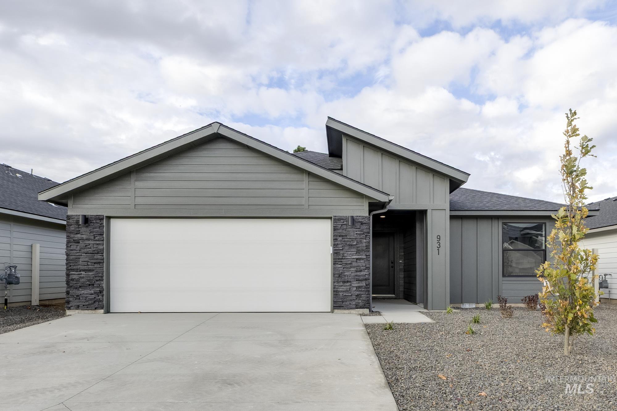 View of front of home with board and batten siding, concrete driveway, a shingled roof, a garage, and stone siding