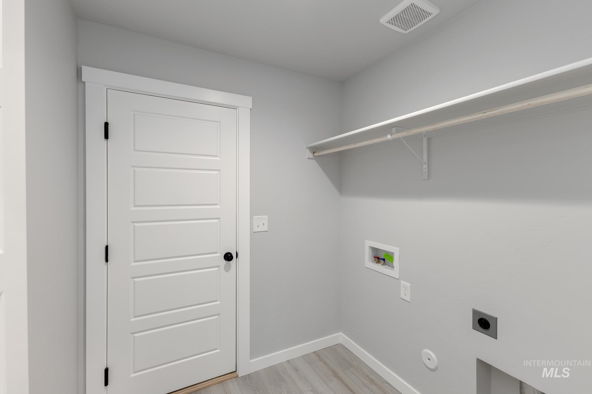 Laundry area with light wood finished floors, hookup for a washing machine, and hookup for an electric dryer