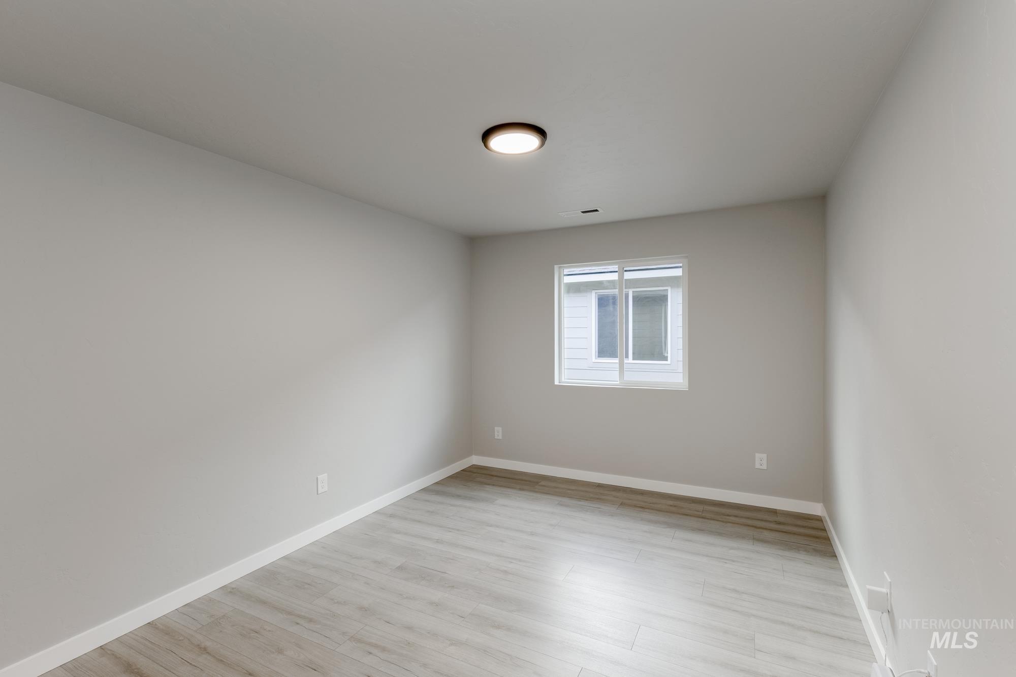 Spare room featuring light wood finished floors and baseboards