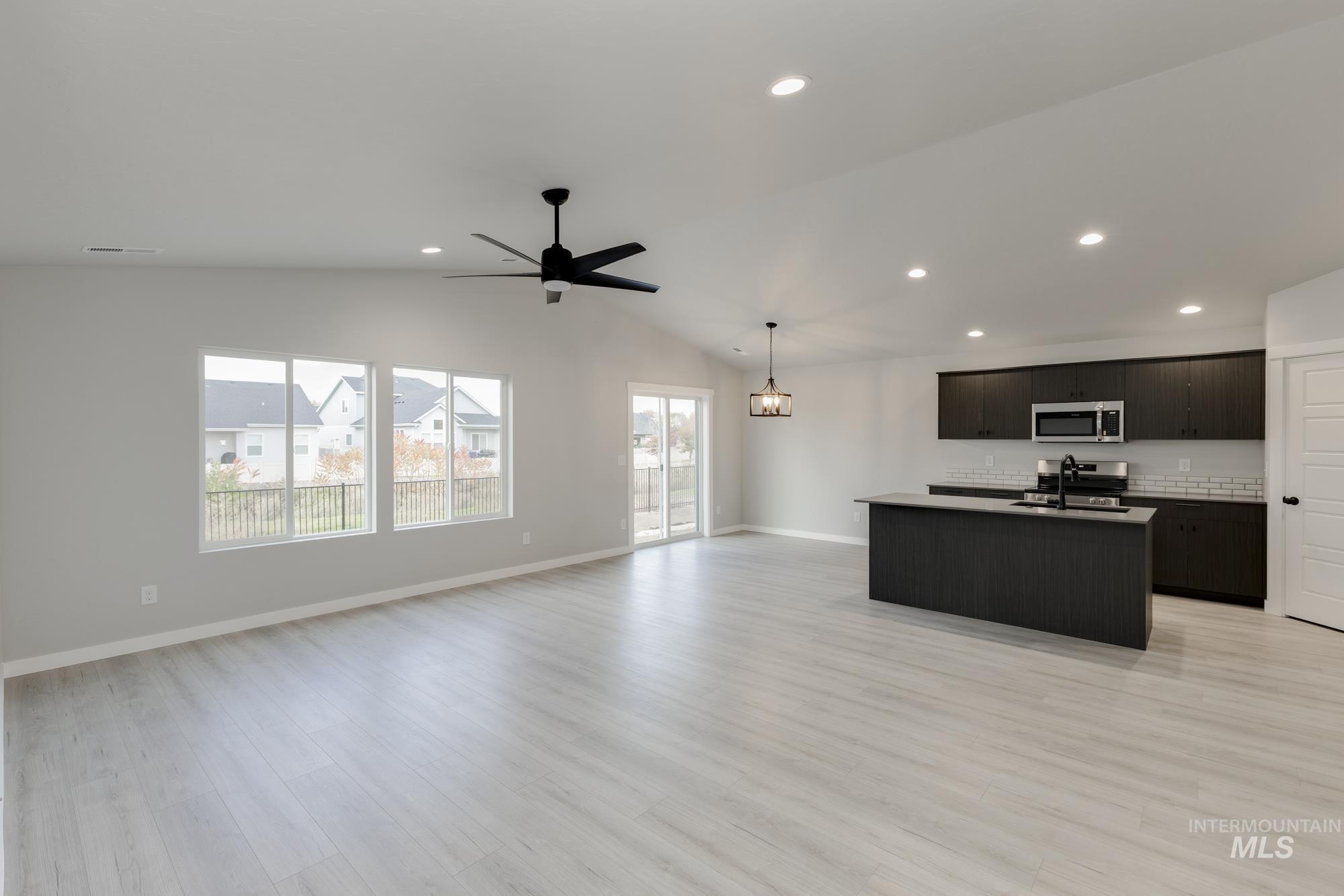 Kitchen with a center island with sink, open floor plan, vaulted ceiling, light wood-type flooring, and recessed lighting