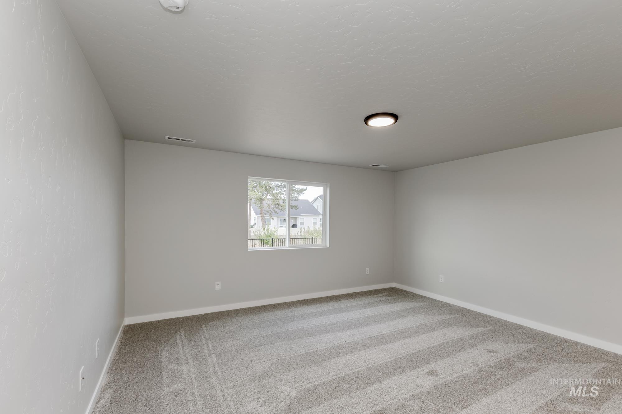 Spare room featuring light carpet and baseboards